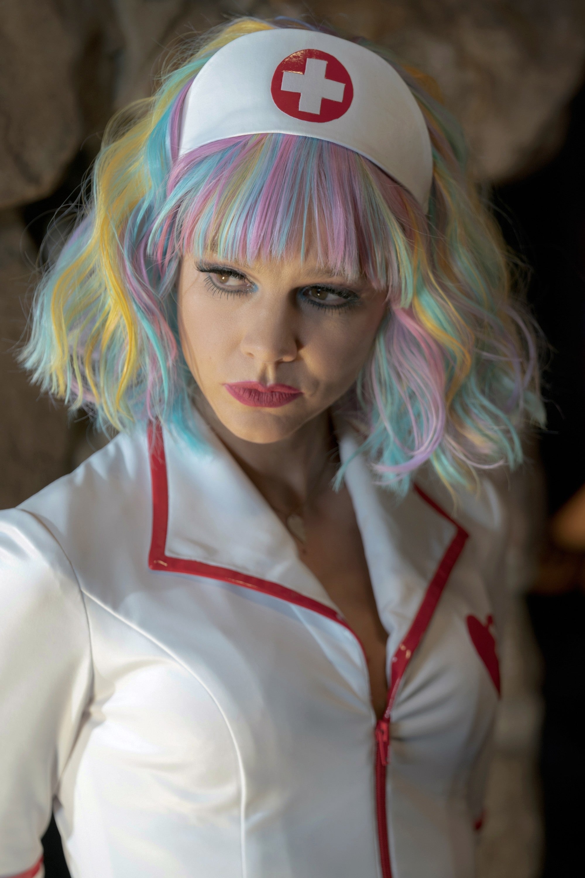 Carey Mulligan in a nurse costume and wild hair looks ahead intently