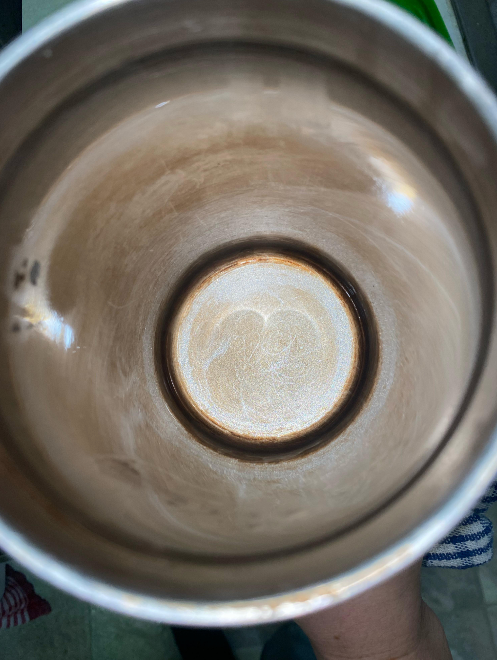 Inside view of a metal cup showing a circular stain at the bottom, suggesting residue from beverages