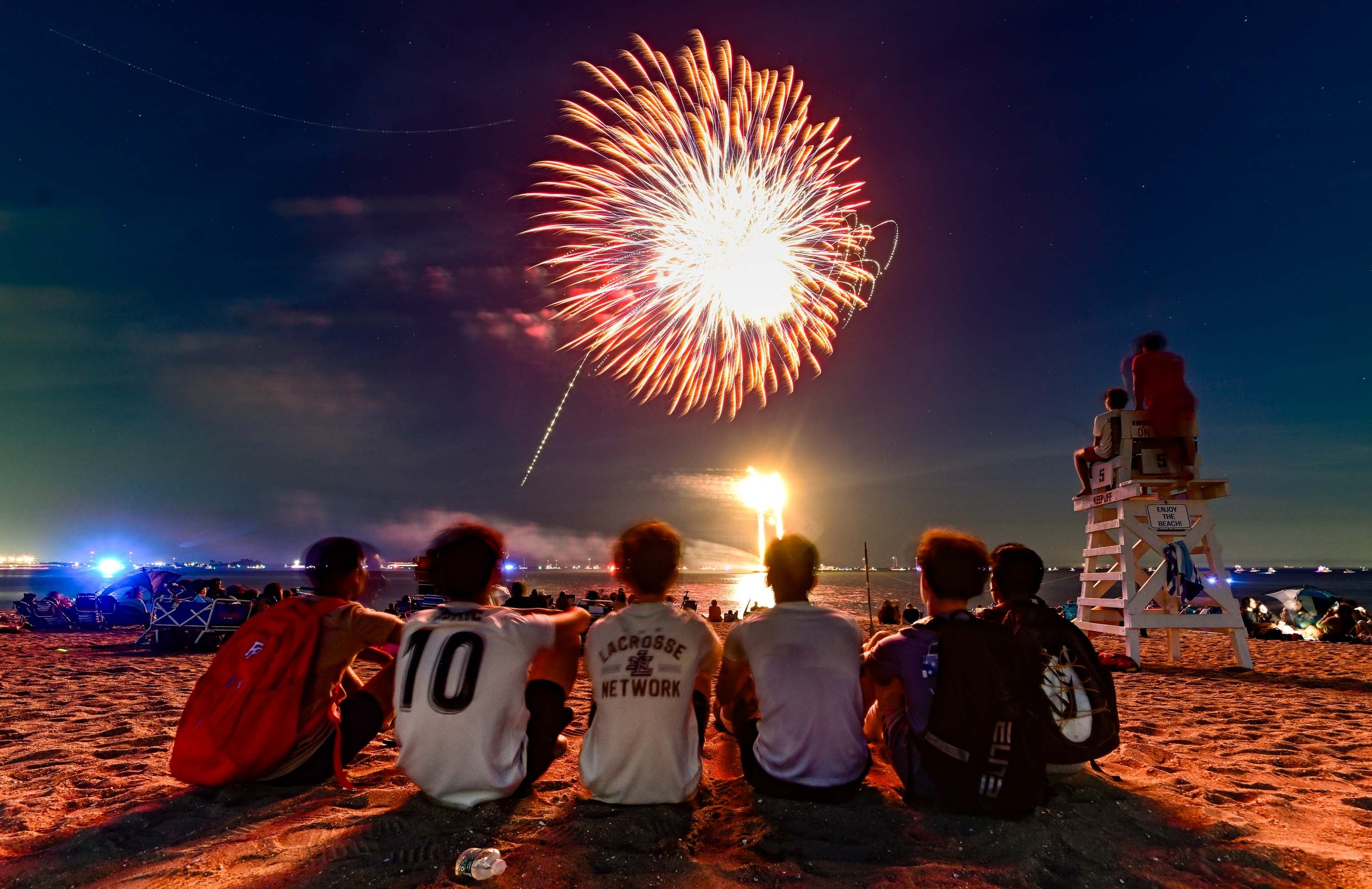 People sitting connected a formation watching a fireworks show successful the nighttime sky