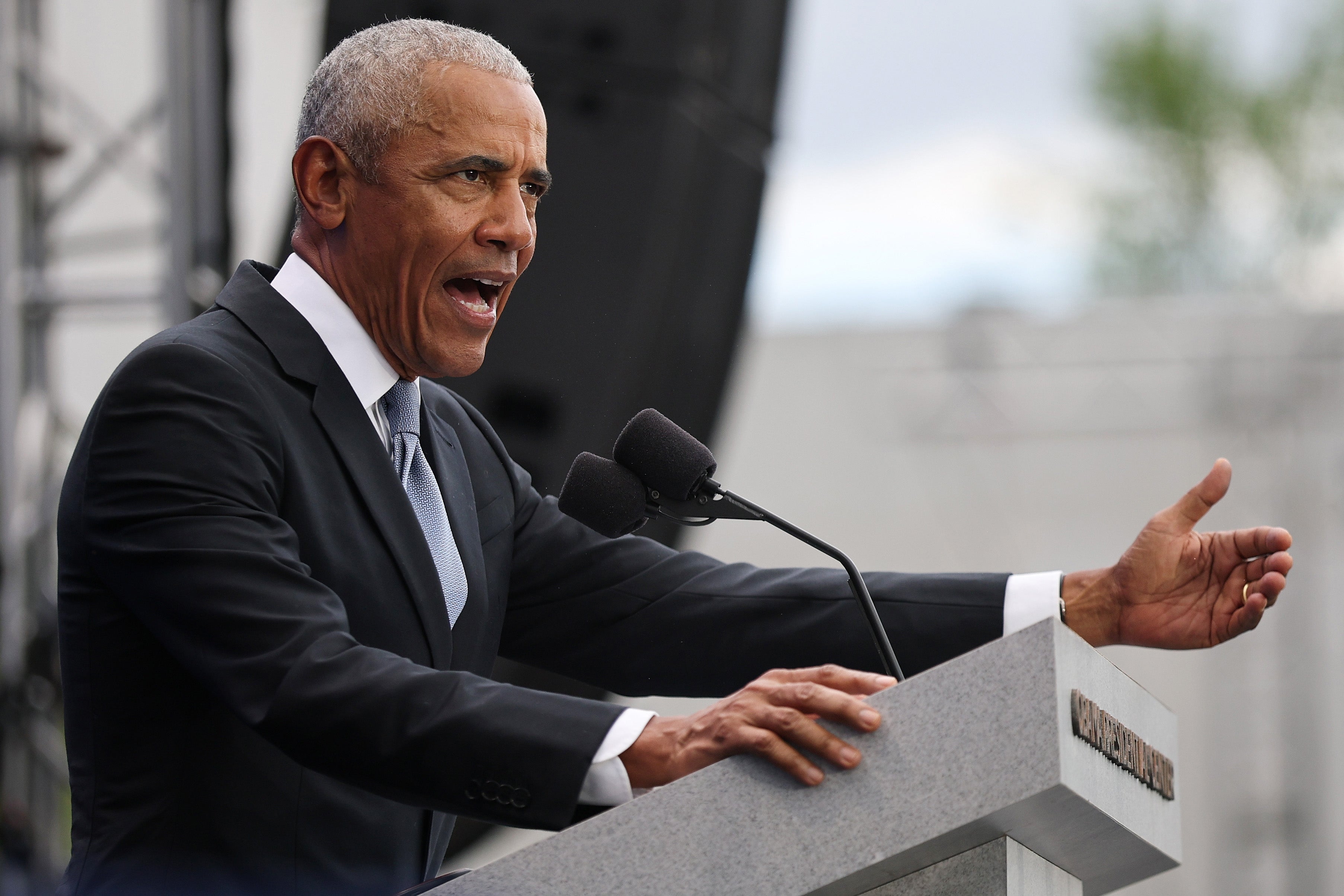 Person successful  a suit   speaking passionately astatine  a podium outdoors