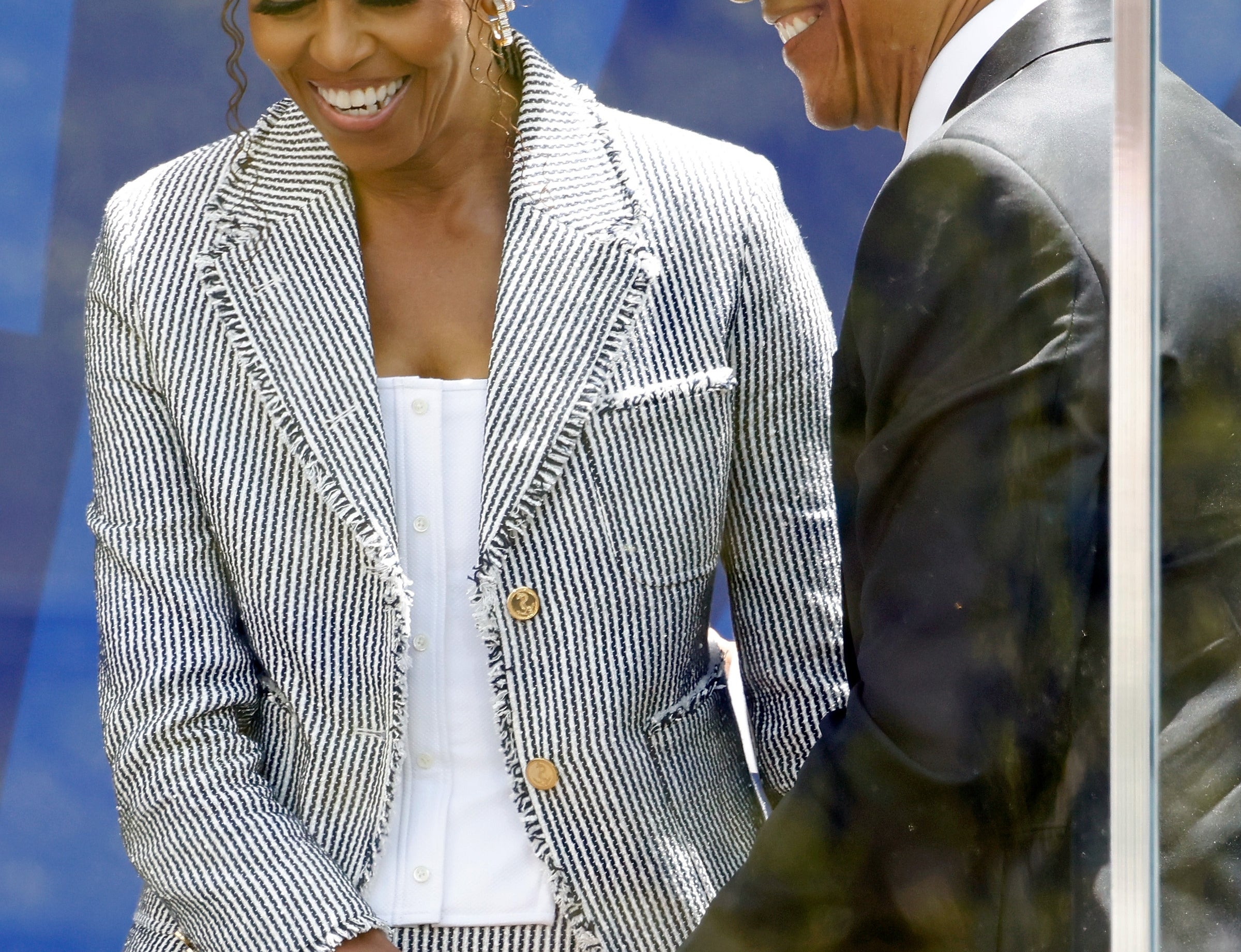 Two radical   are smiling and holding hands. One is wearing a patterned suit; the different   is successful  a acheronian  suit. They look  to beryllium  astatine  a ceremonial  event