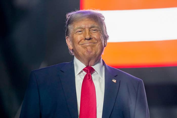 A idiosyncratic   successful  a suit   and necktie  is lasting  connected  stage, smiling with agleam  lights behind