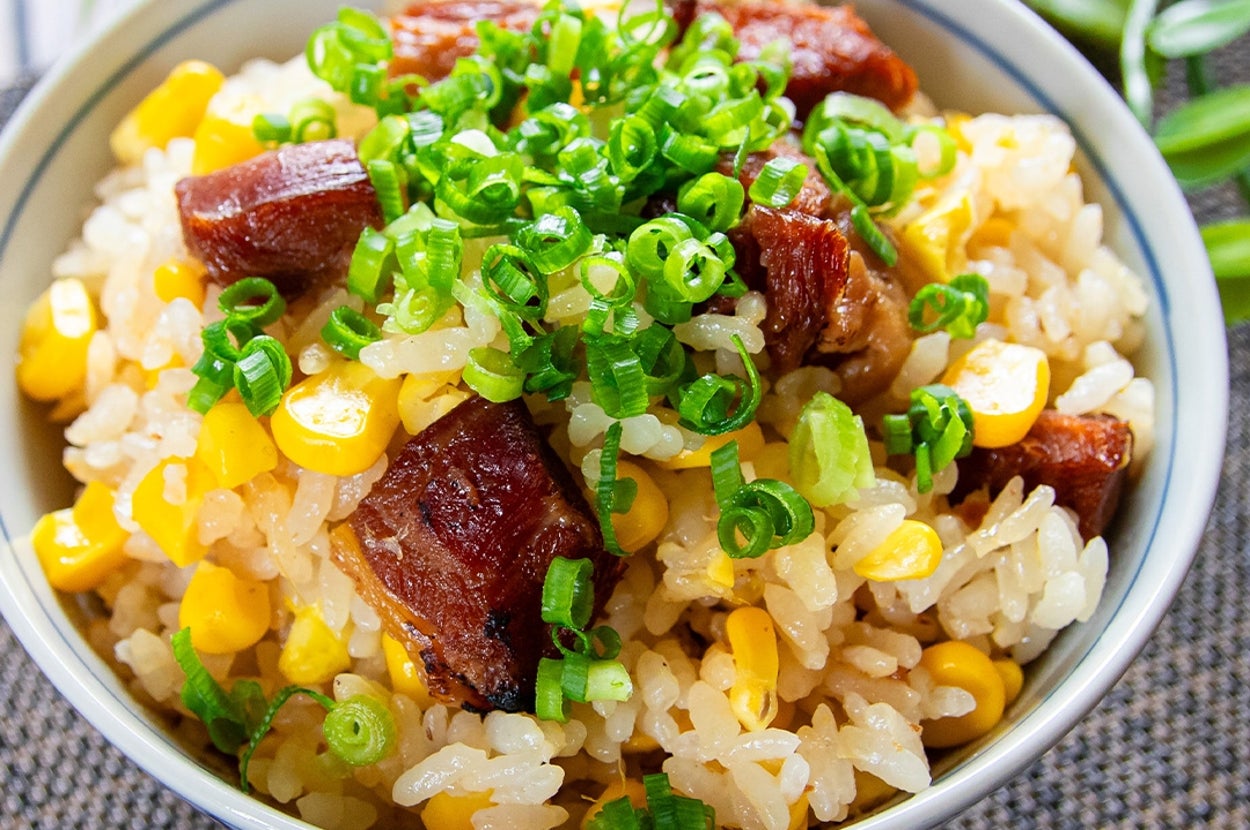 焼き鳥とコーンが入った炊き込みご飯が器に盛られている。青ねぎが上に散らされている。