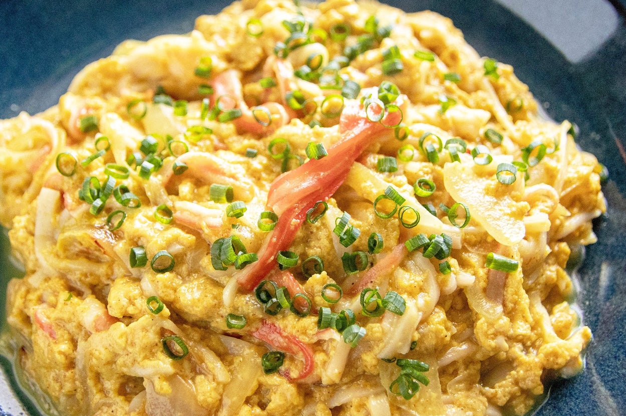 青い皿に盛られたうどんと卵の炒め物。刻みネギがトッピングされています。