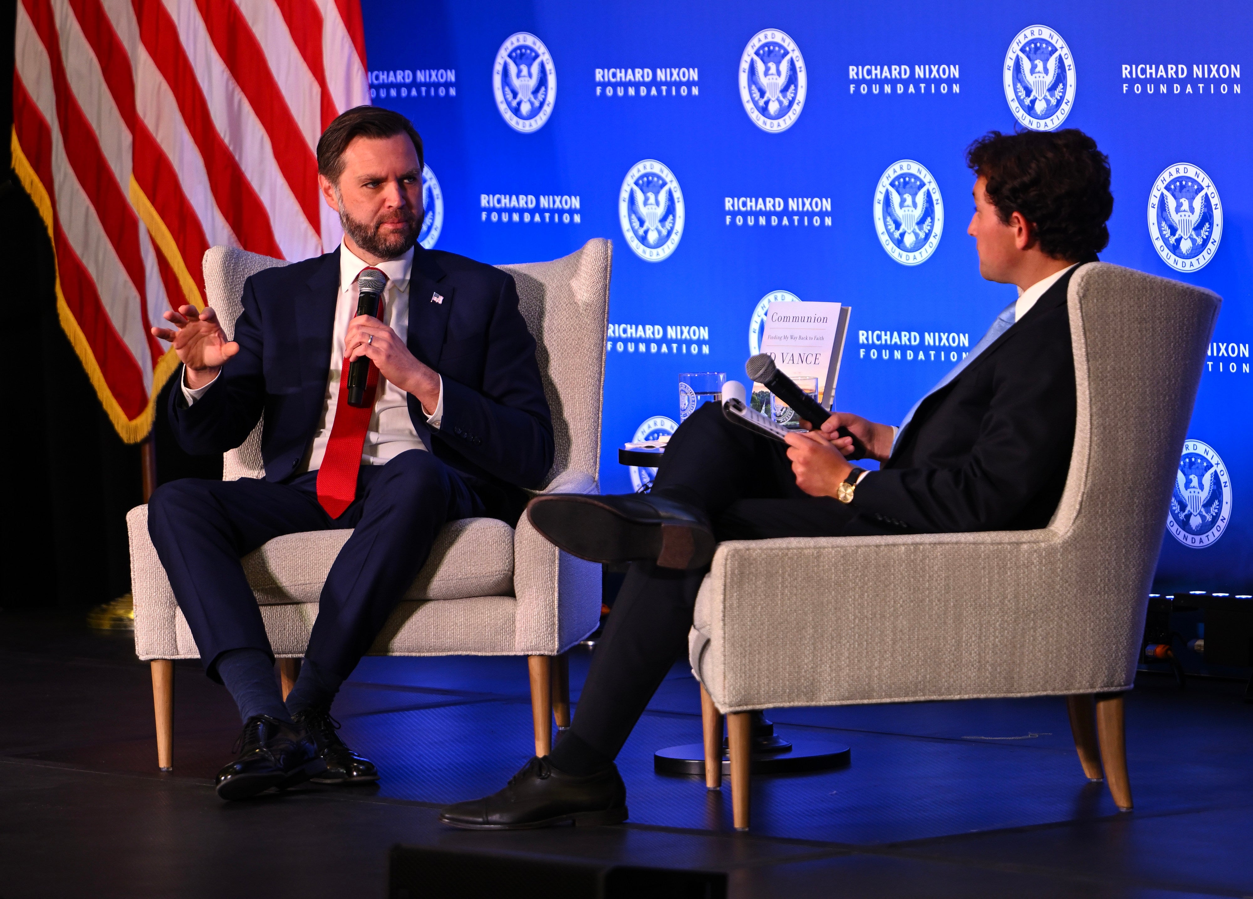 Two individuals seated, engaged successful  a treatment  connected  signifier    astatine  a Richard Nixon Foundation event