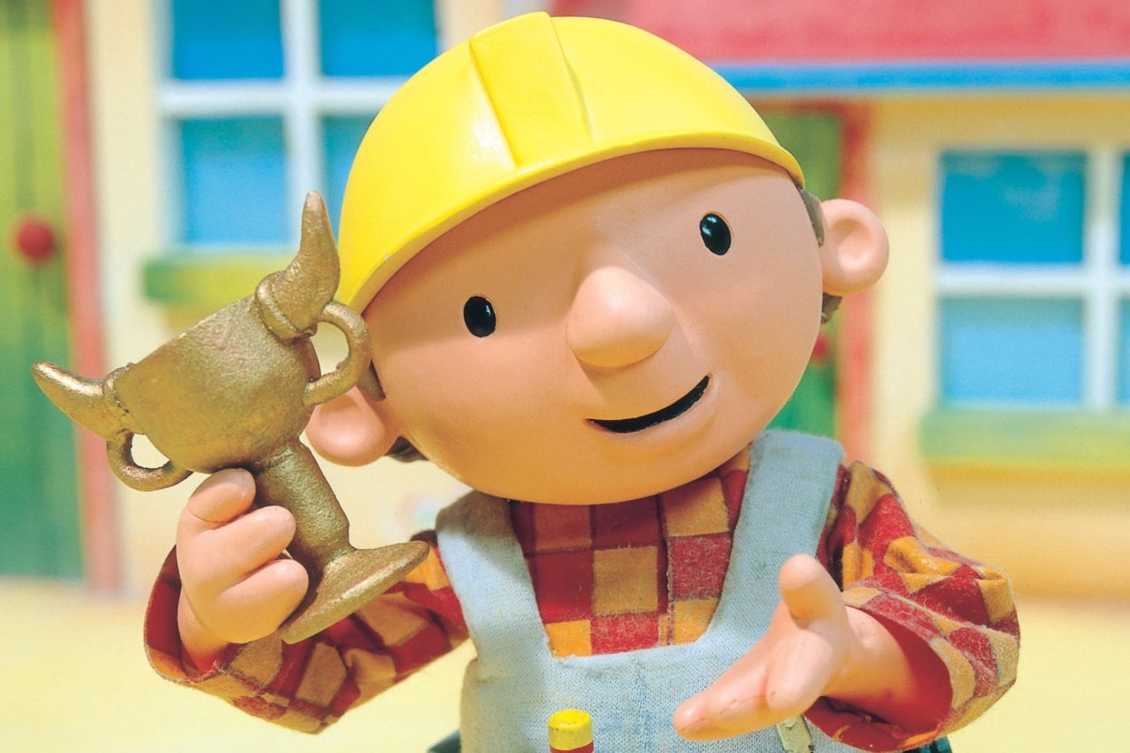 Animated character wearing a hard hat and overalls, holding a small trophy, smiling in front of a house backdrop