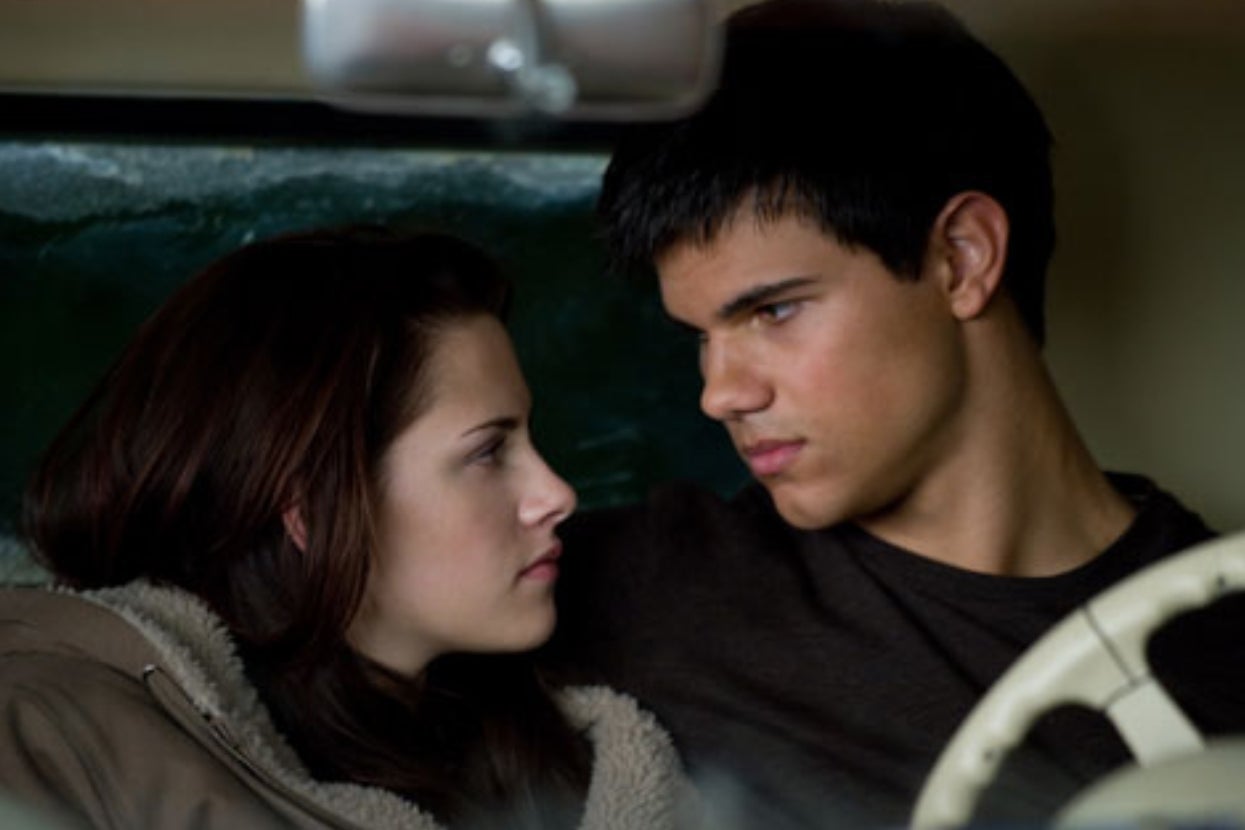 Two people sit closely in a car, gazing intently at each other