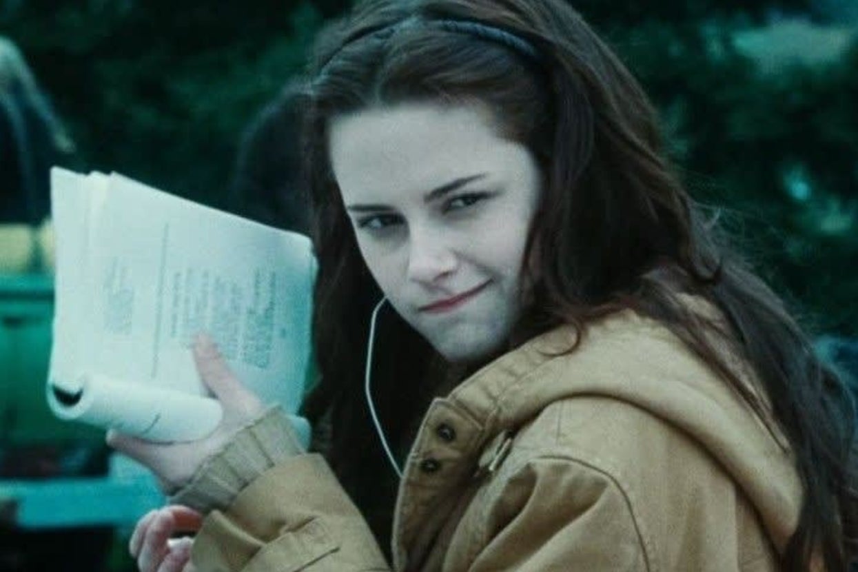 Person in a jacket holding papers outdoors, with an inquisitive expression, listening to something with headphones