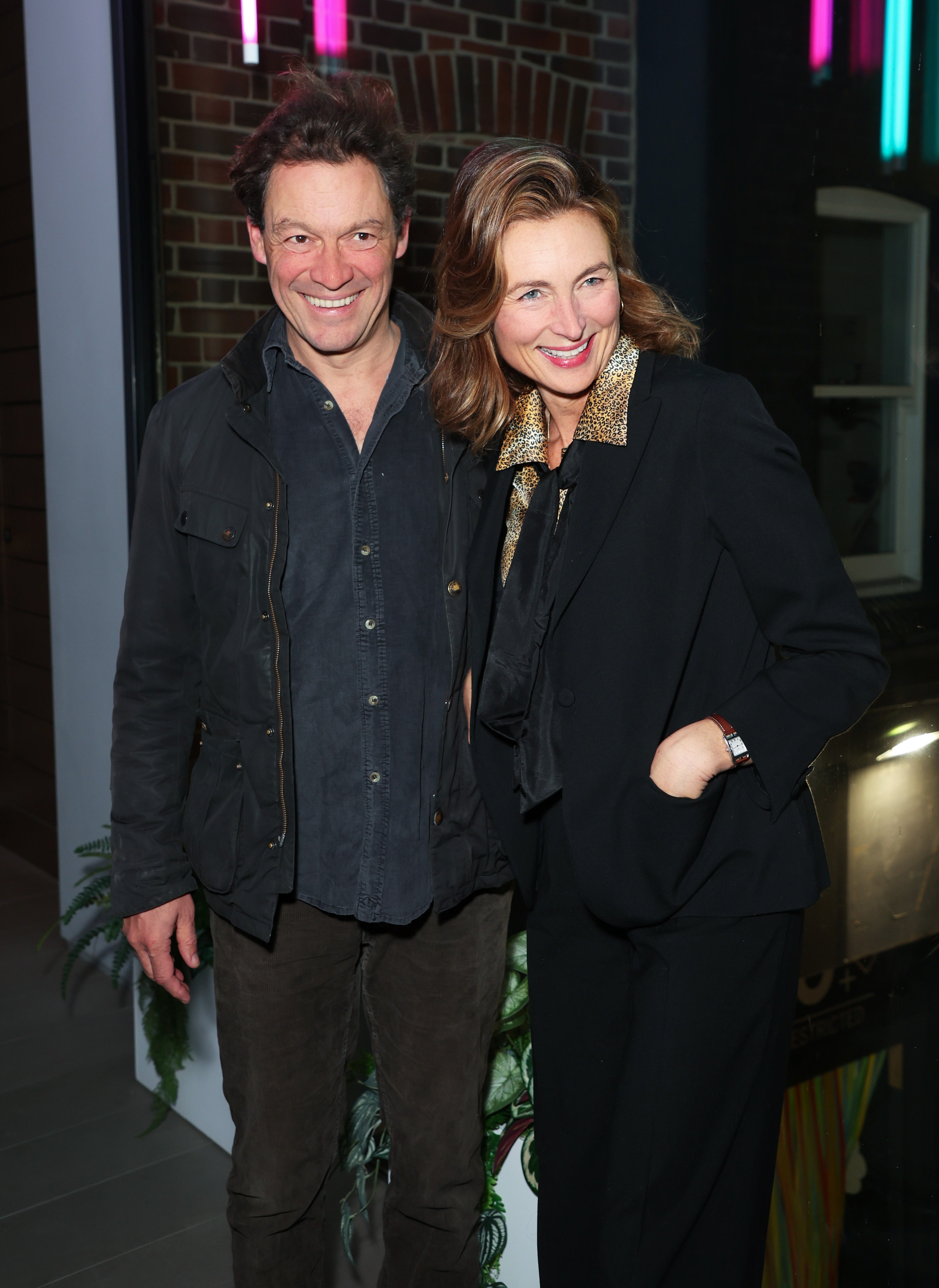 Dominic West and Catherine FitzGerald smiling outside of a building