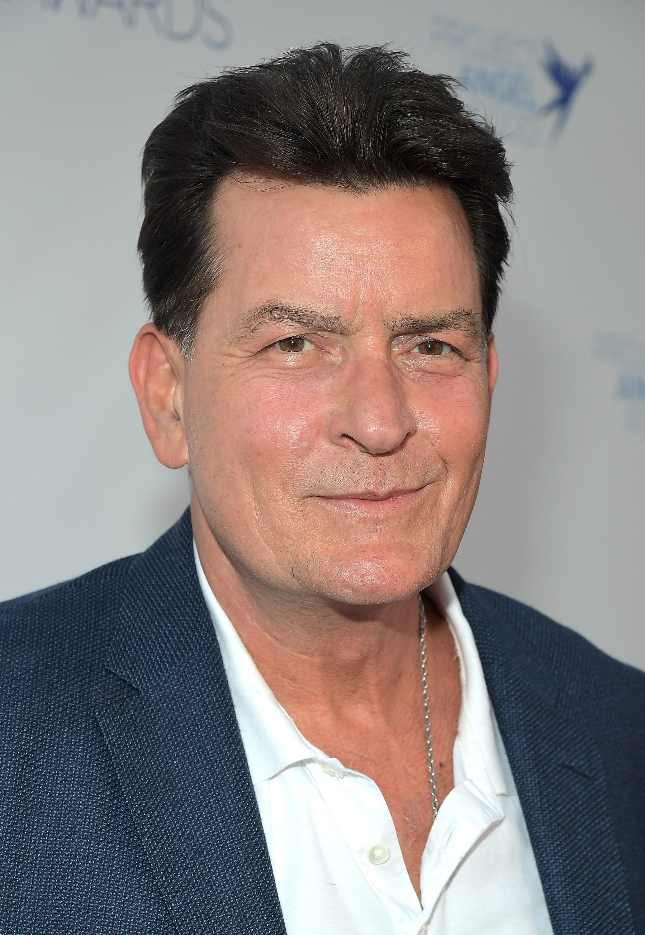 Man in a white shirt and dark blazer, with a slight smile, attending an event