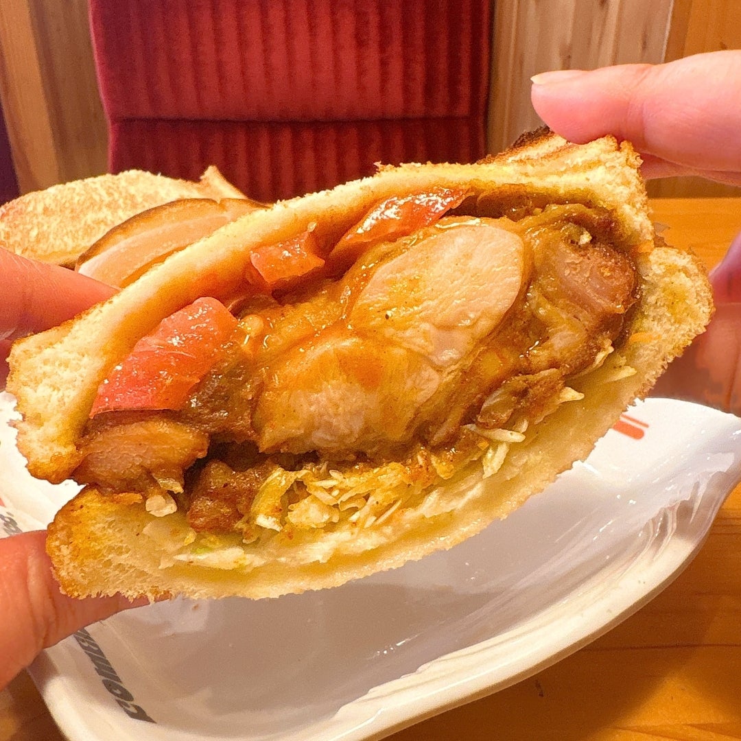 コメダ珈琲店の「タンドリーチキンホットサンド」の中身を見せた断面図。キャベツ、トマト、チキンが見える。