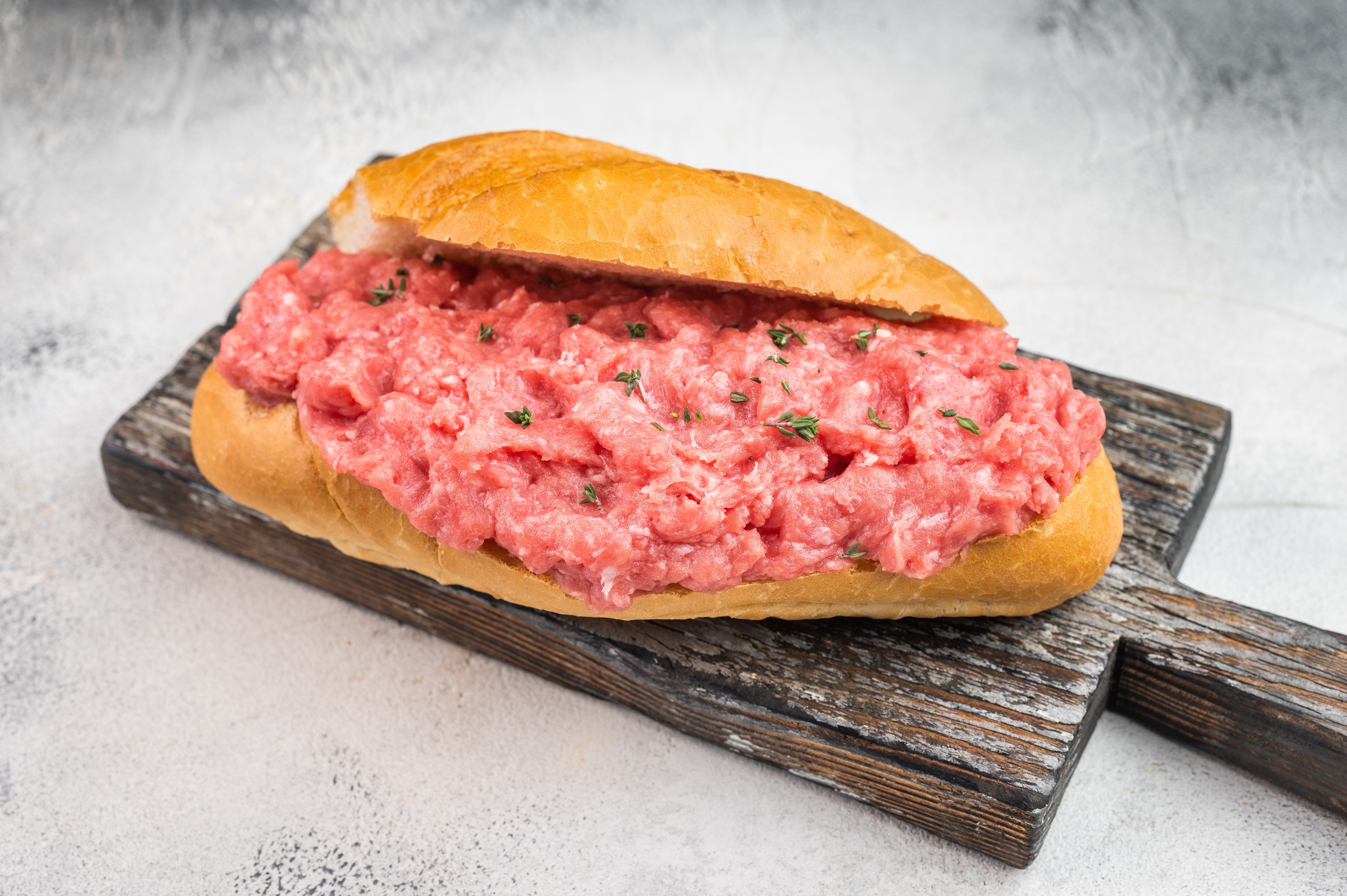 Open sandwich with earthy minced nutrient connected a baguette, garnished with herbs, placed connected a woody board