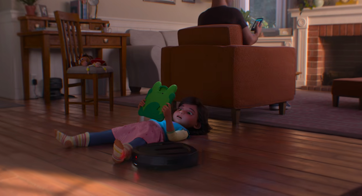 Child lies on living room floor, tablet in hand, while an adult nearby looks at a phone, highlighting a cozy, tech-focused domestic scene