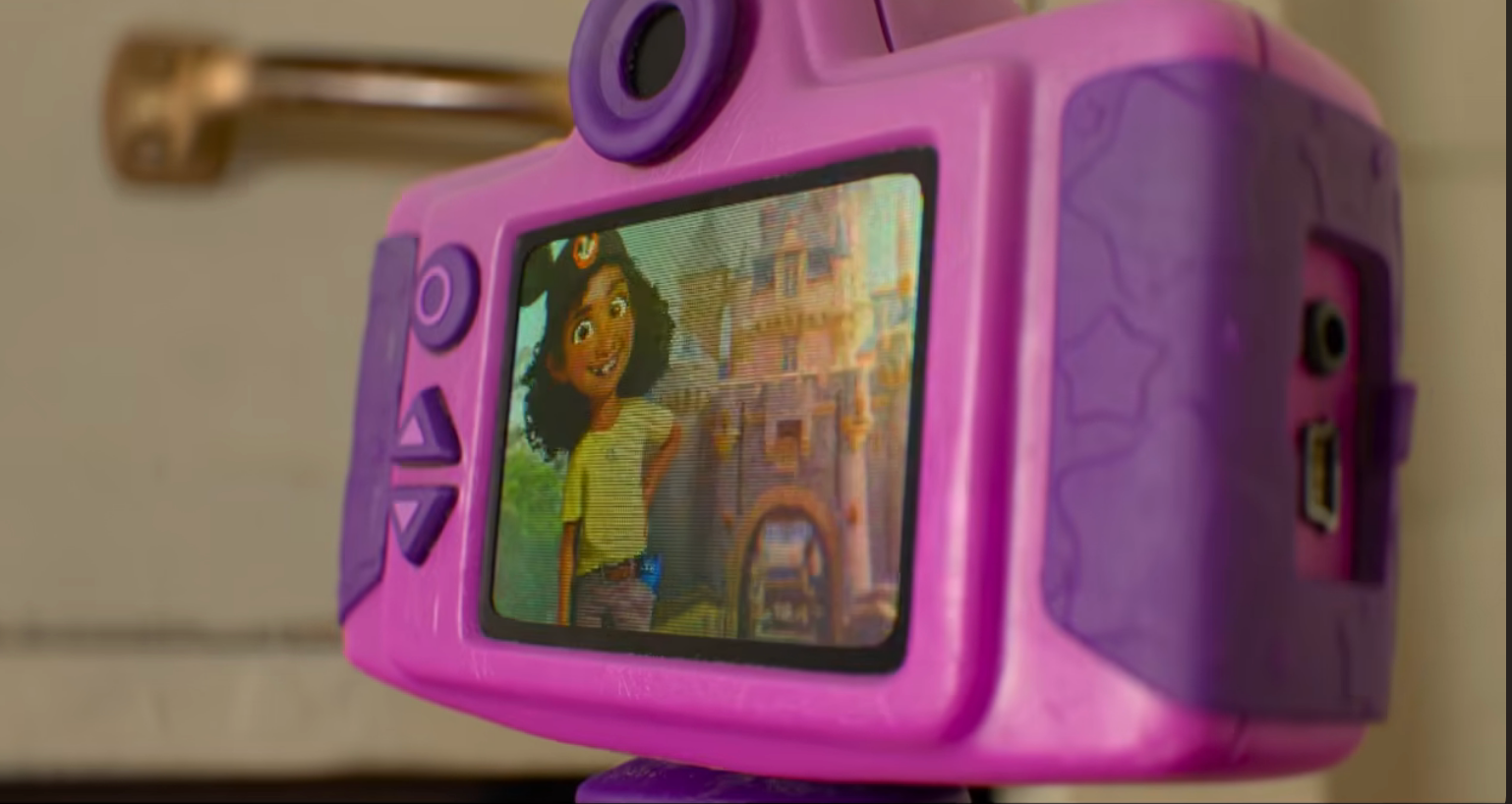 Close-up of a toy camera screen showing an animated scene with a child standing in front of a castle