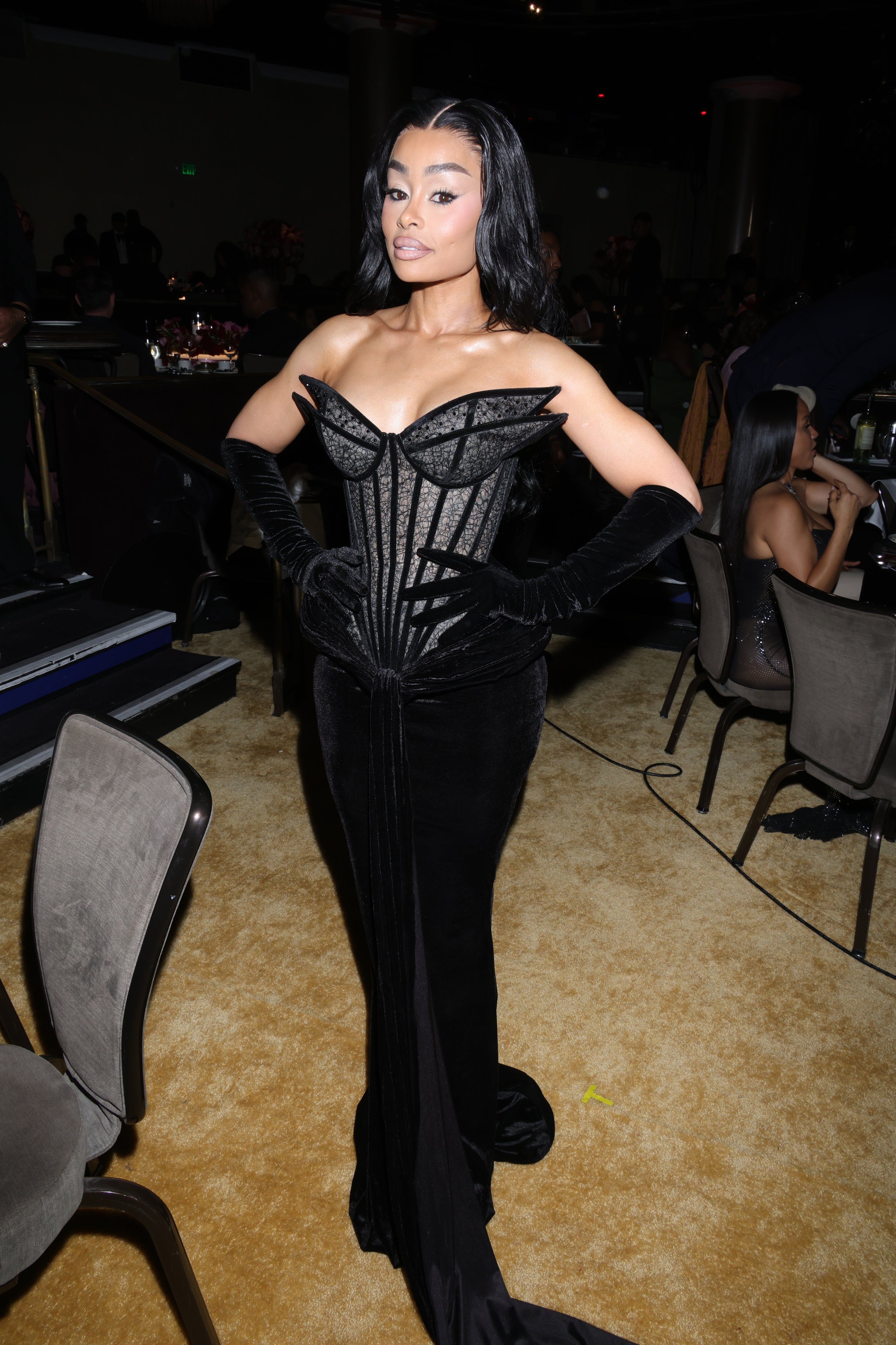 Blac Chyna in an elegant, form-fitting velvet gown with structured detailing poses confidently at a formal event