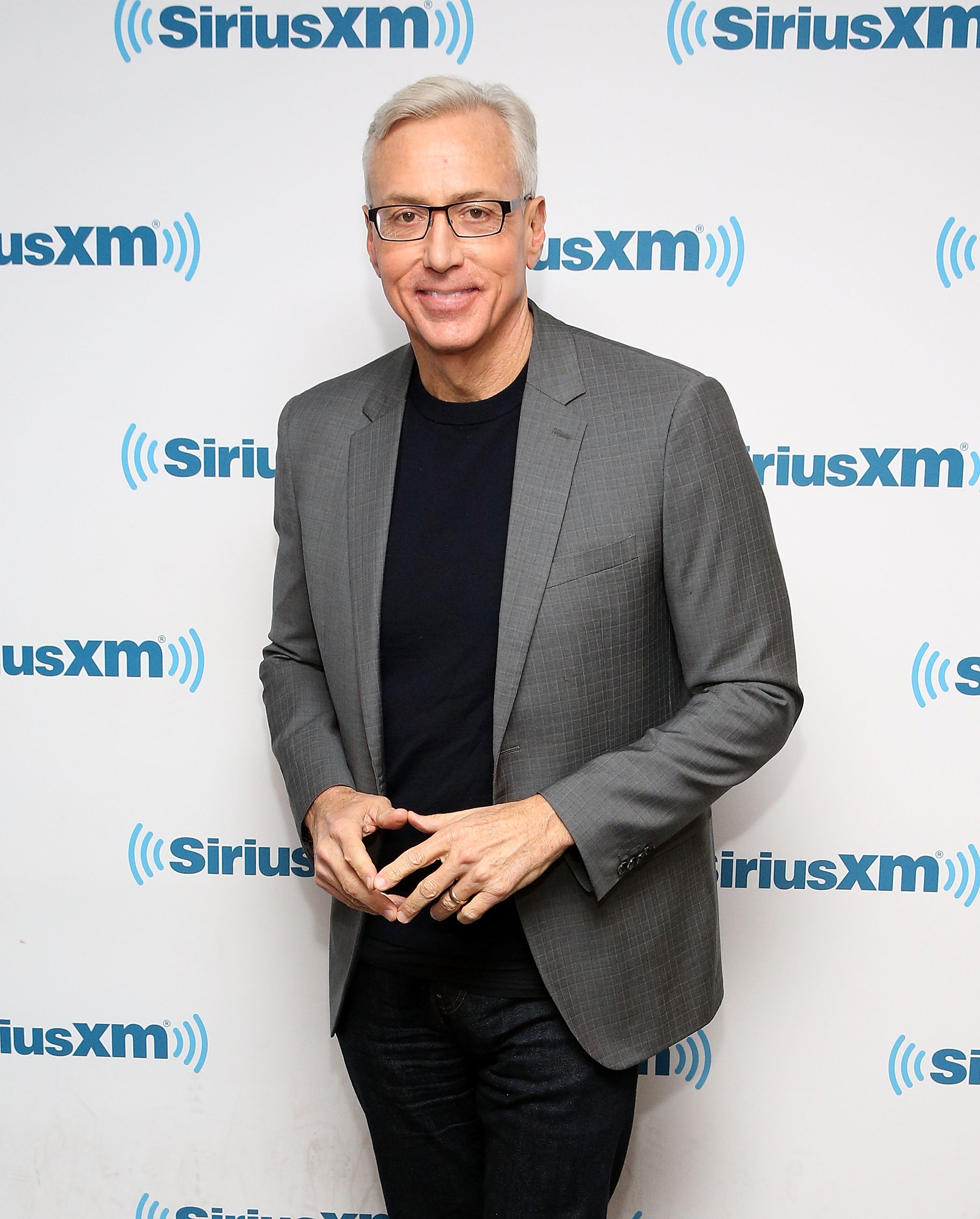 Dr. Drew Pinksy successful  a blazer and garment  posing successful  beforehand   of a SiriusXM backdrop