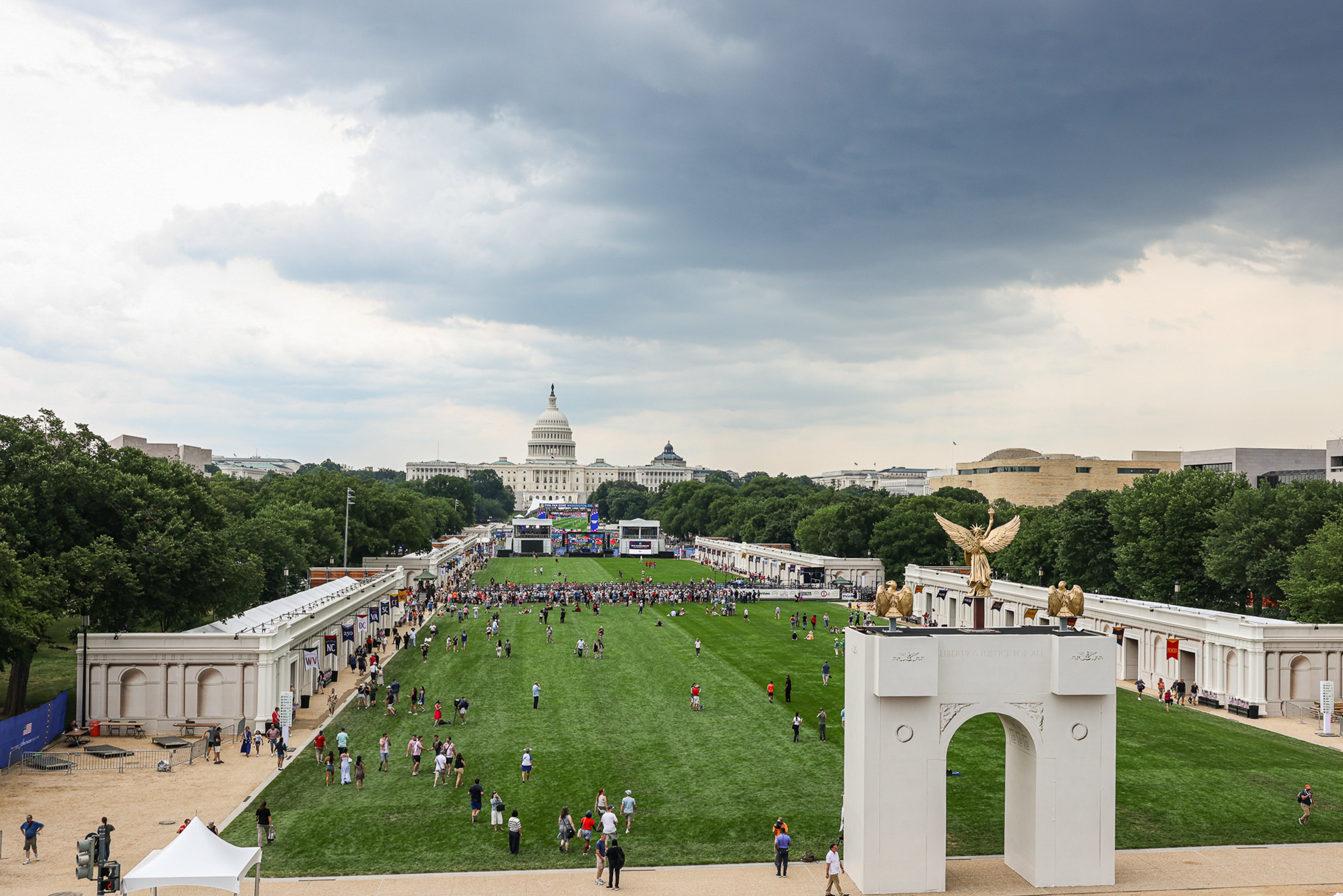 Vid utsikt over National Mall vendt mot US Capitol, med folk samlet på gresset under en overskyet himmel