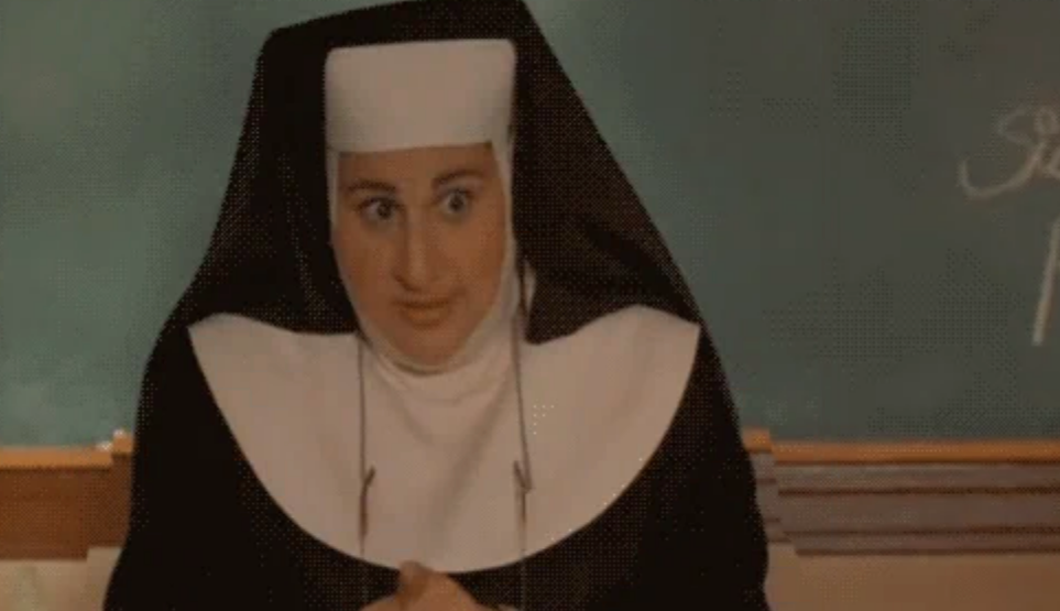 En person utkledd som en nonne står foran en tavle med et lekent uttrykk