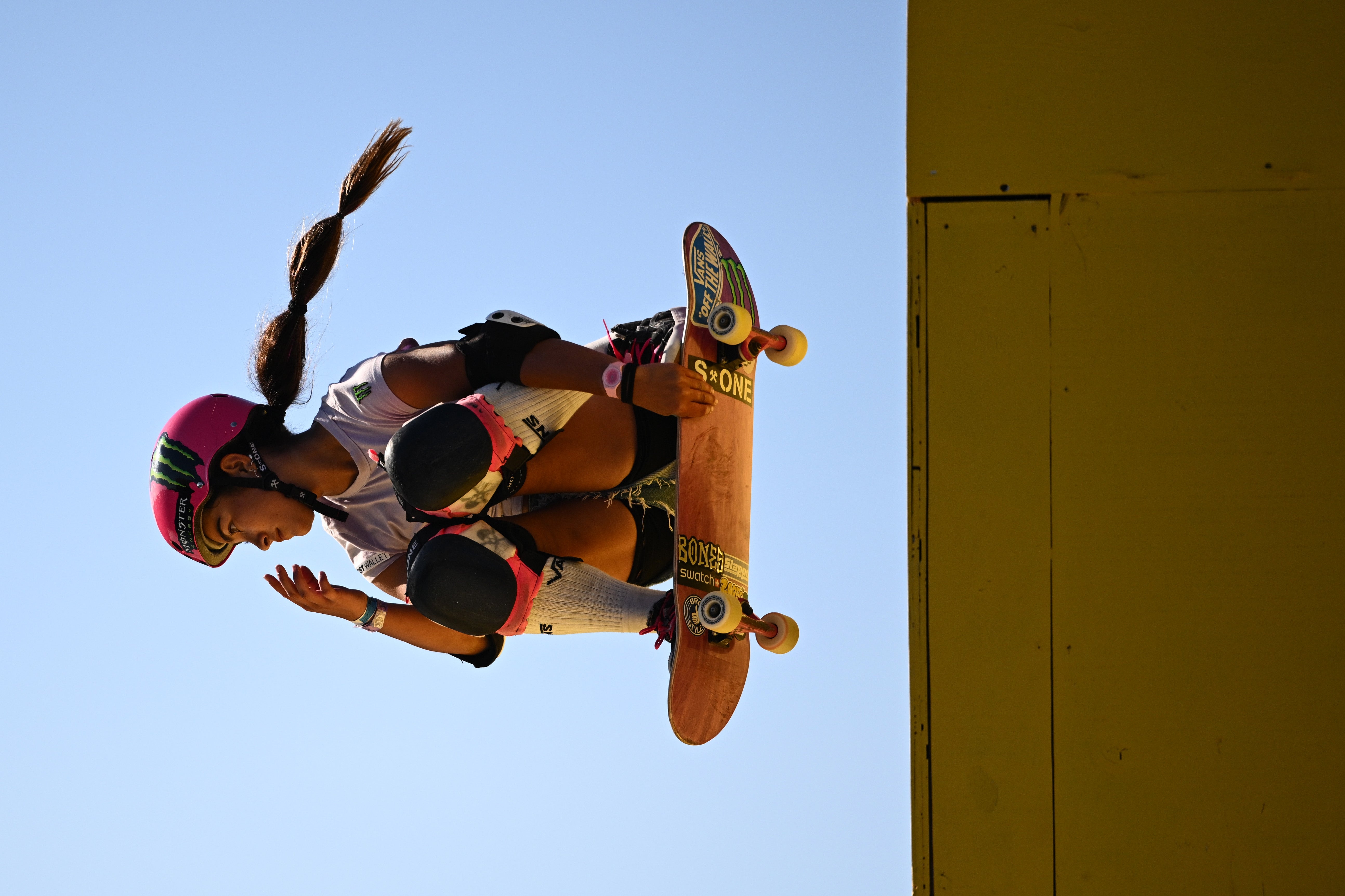 A skateboarder mid-air performing a instrumentality   connected  a ramp, wearing a helmet, pads, and casual sportswear