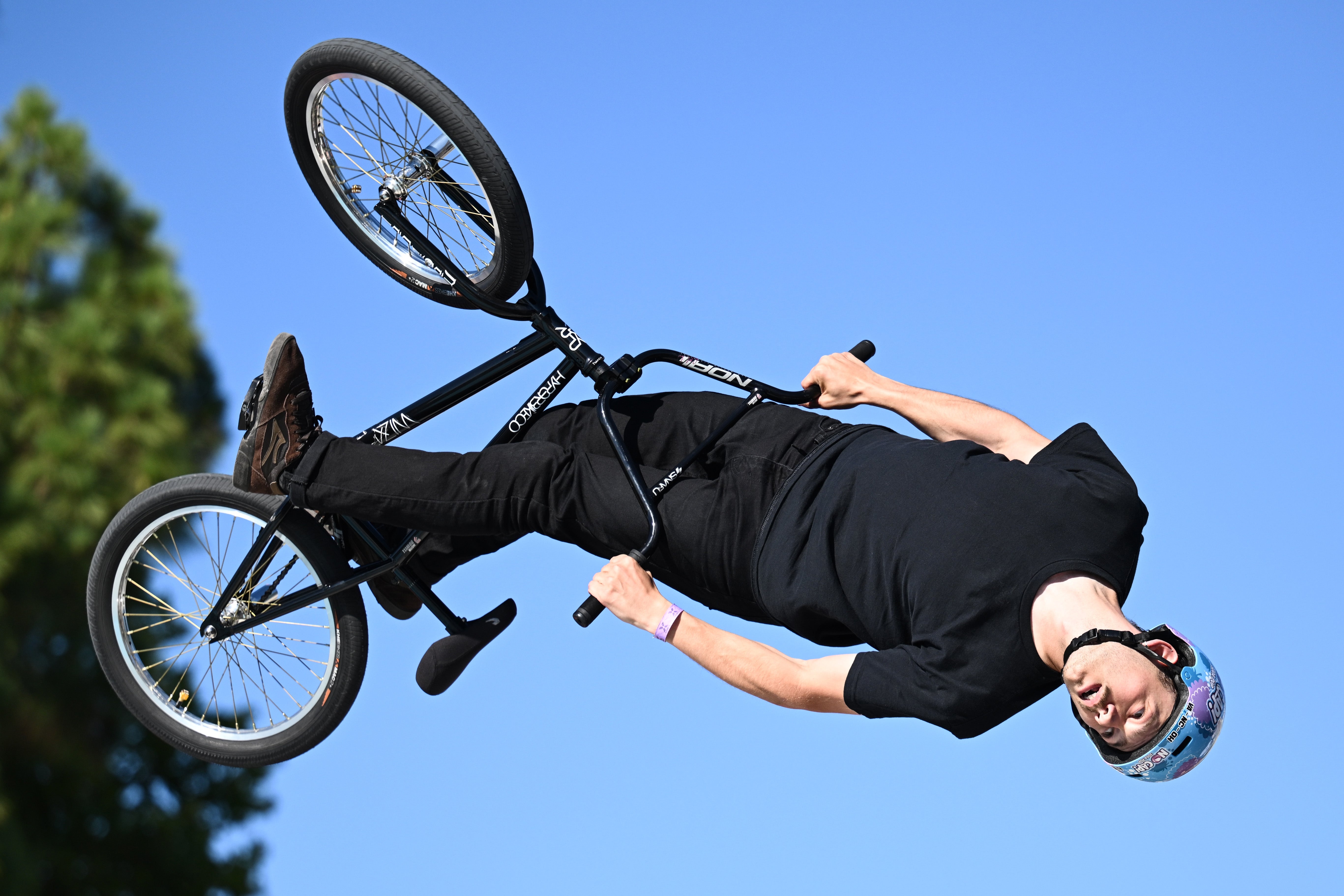 Person performing an aerial instrumentality   connected  a BMX bike, upside down   successful  mid-air, wearing a helmet and casual attire
