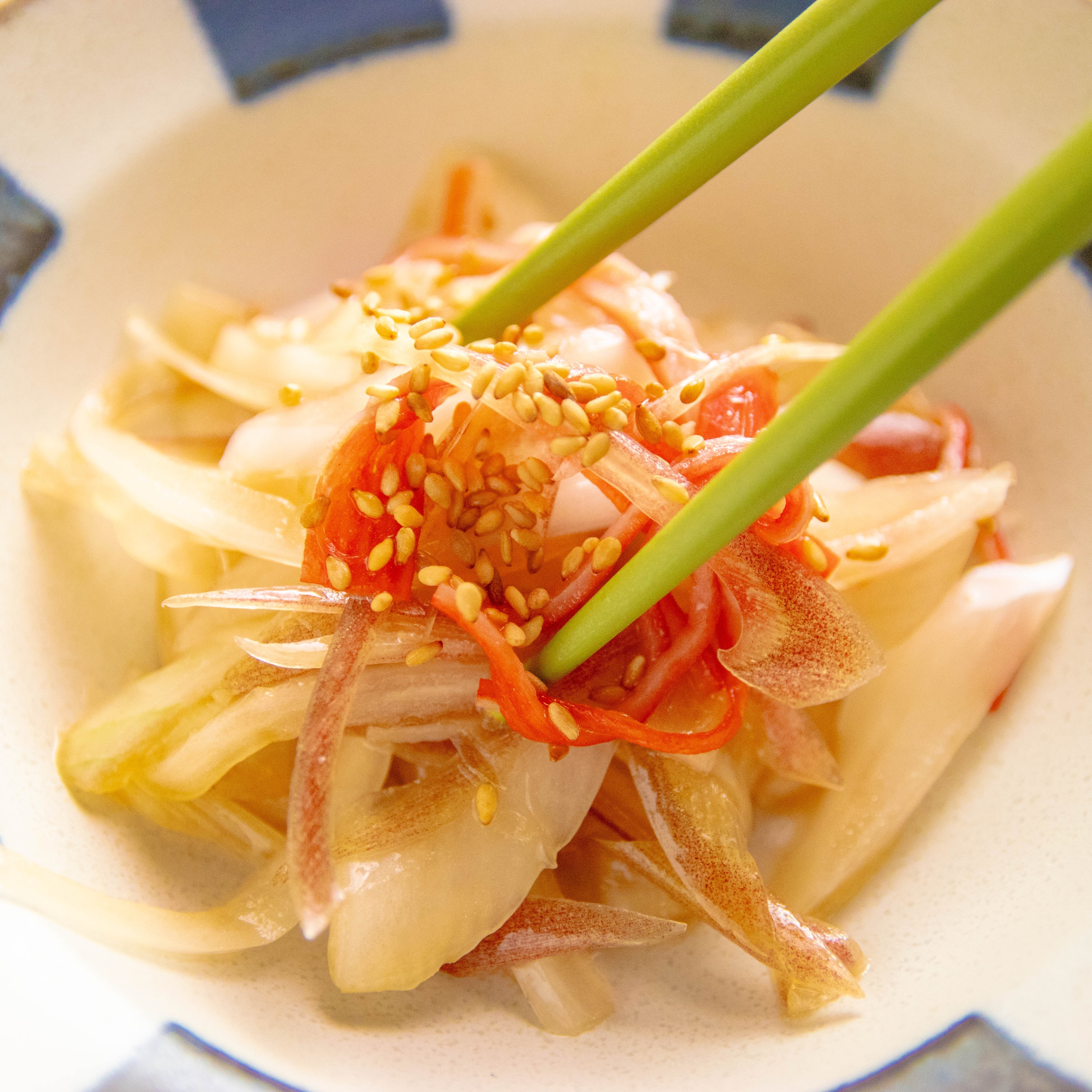 箸でひと口分を持ち上げられた、みずみずしいみょうがと玉ねぎ、カニ風味かまぼこのポン酢サラダ