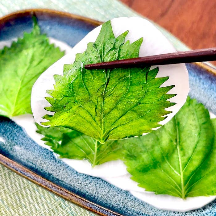 皿に大根とシソの葉が盛られ、箸で摘まれています。