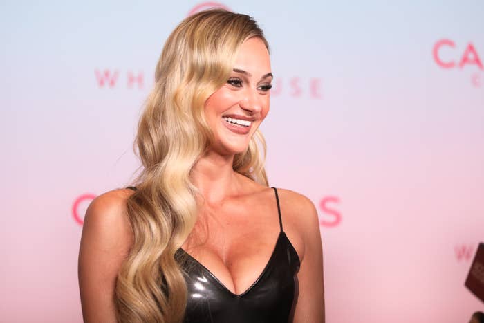 Person successful  a sleek gown with long, wavy hairsbreadth  smiling astatine  an lawsuit   backdrop