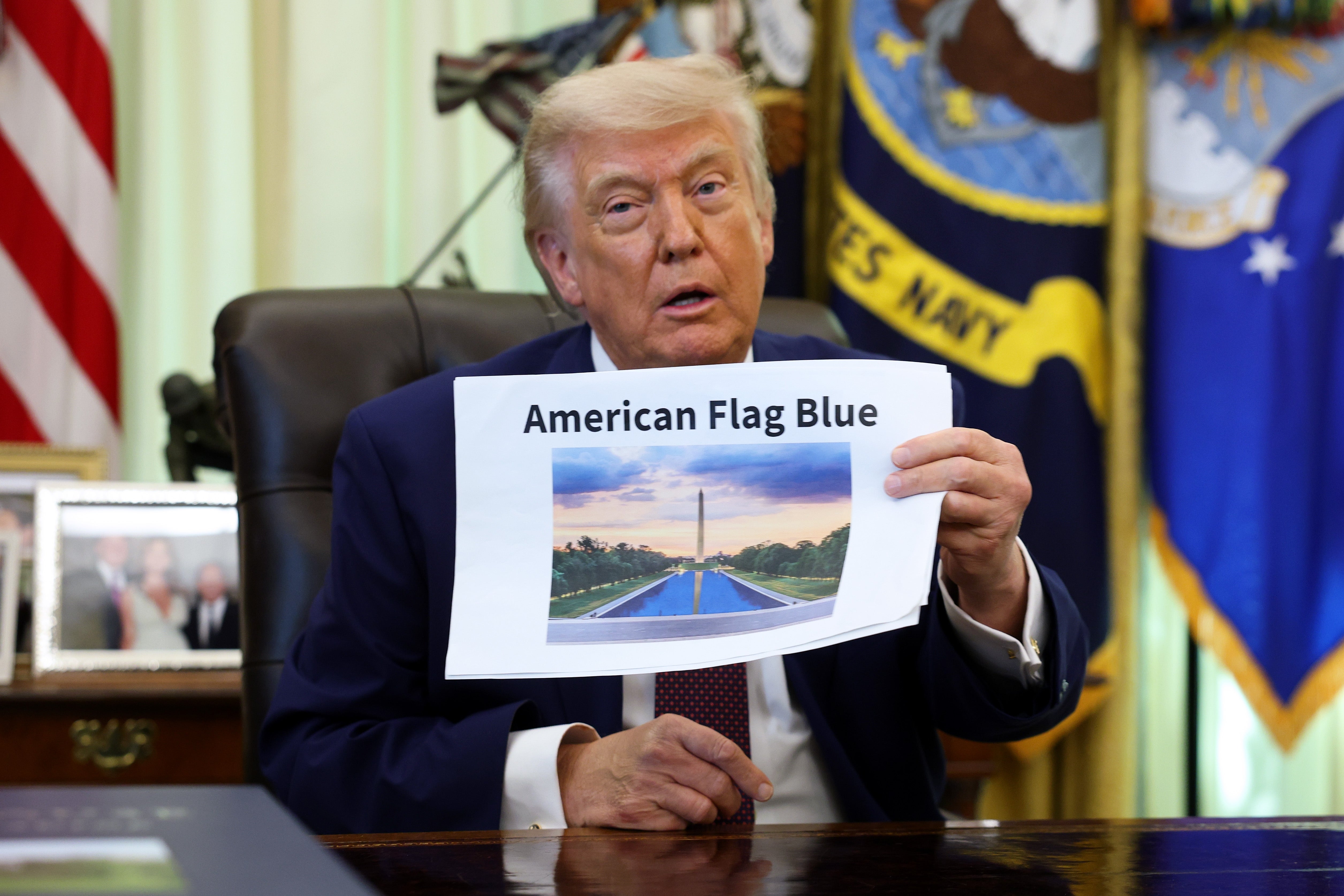 A idiosyncratic   sits astatine  a table  successful  an authoritative  setting, holding a insubstantial  showing an representation  labeled "American Flag Blue."