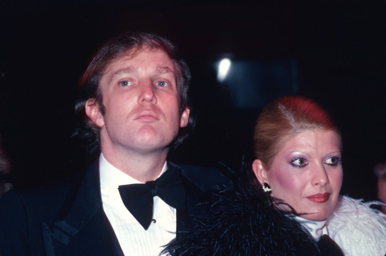 Two people at a formal event; one wears a tuxedo with a bow tie, the other a feathered outfit