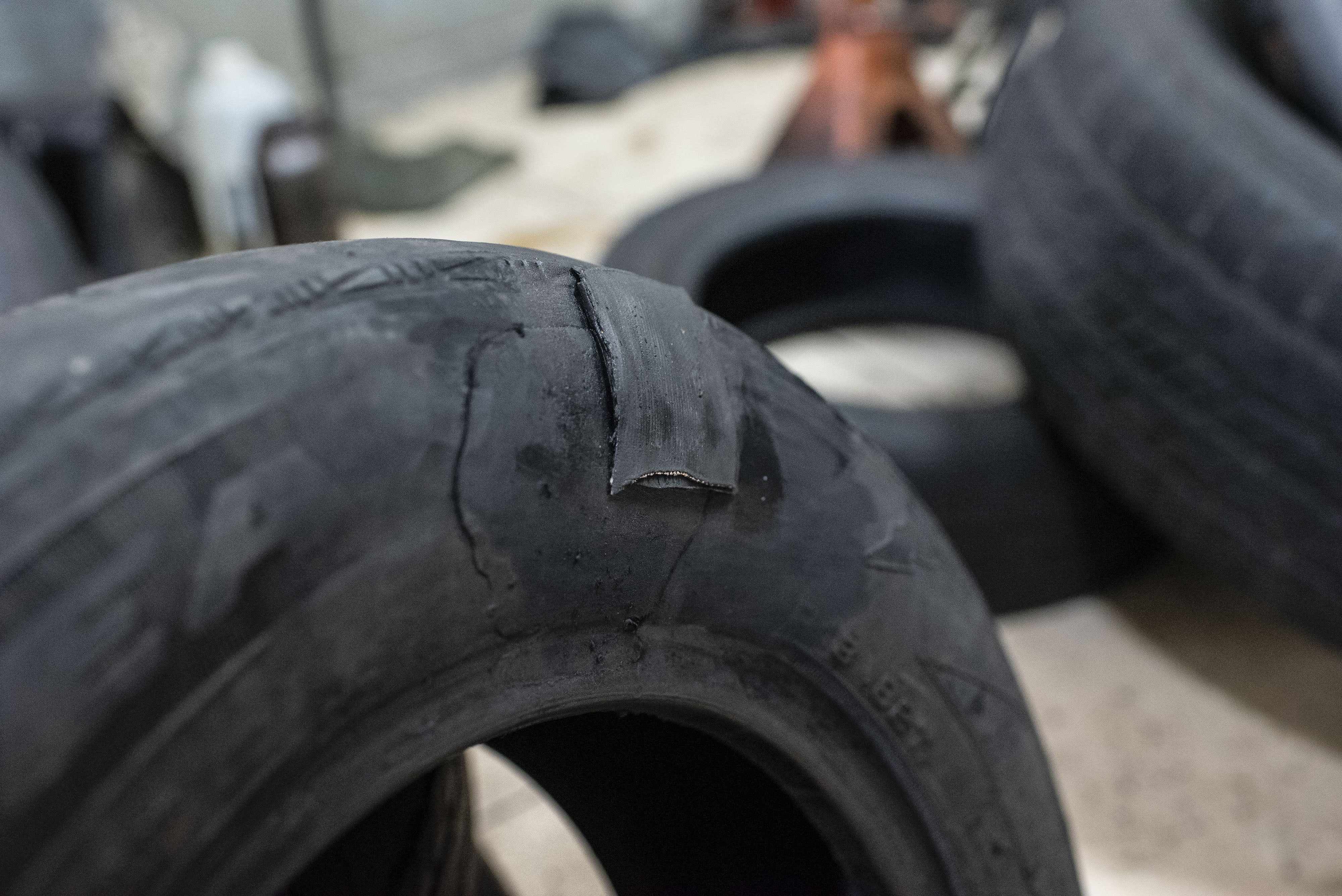 Close-up of a worn car tyre with disposable cracks and divided tread, surrounded by different tires successful a store setting