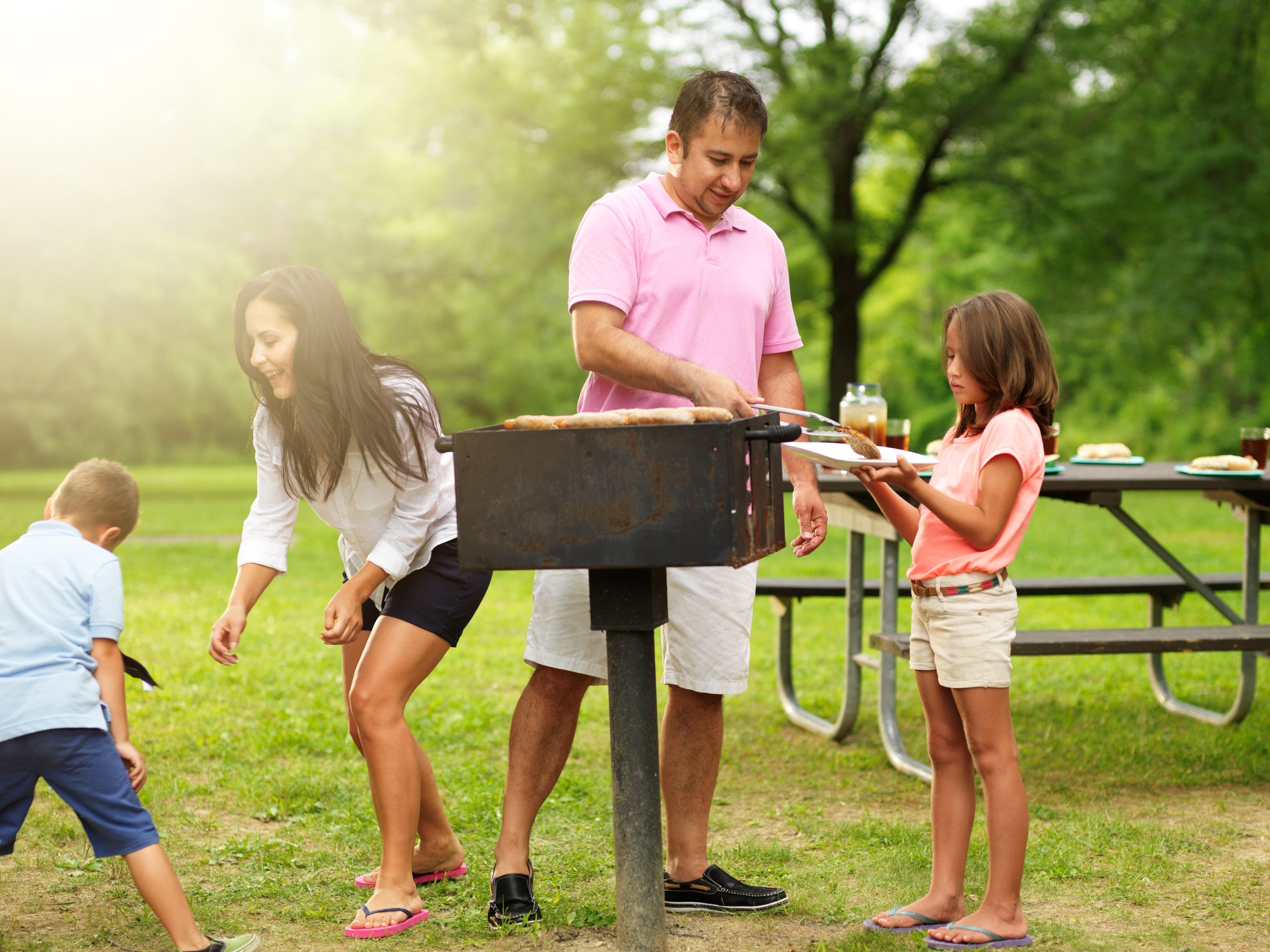 Family having a barbecue successful a park, with 1 idiosyncratic grilling portion others stitchery around, enjoying the picnic atmosphere
