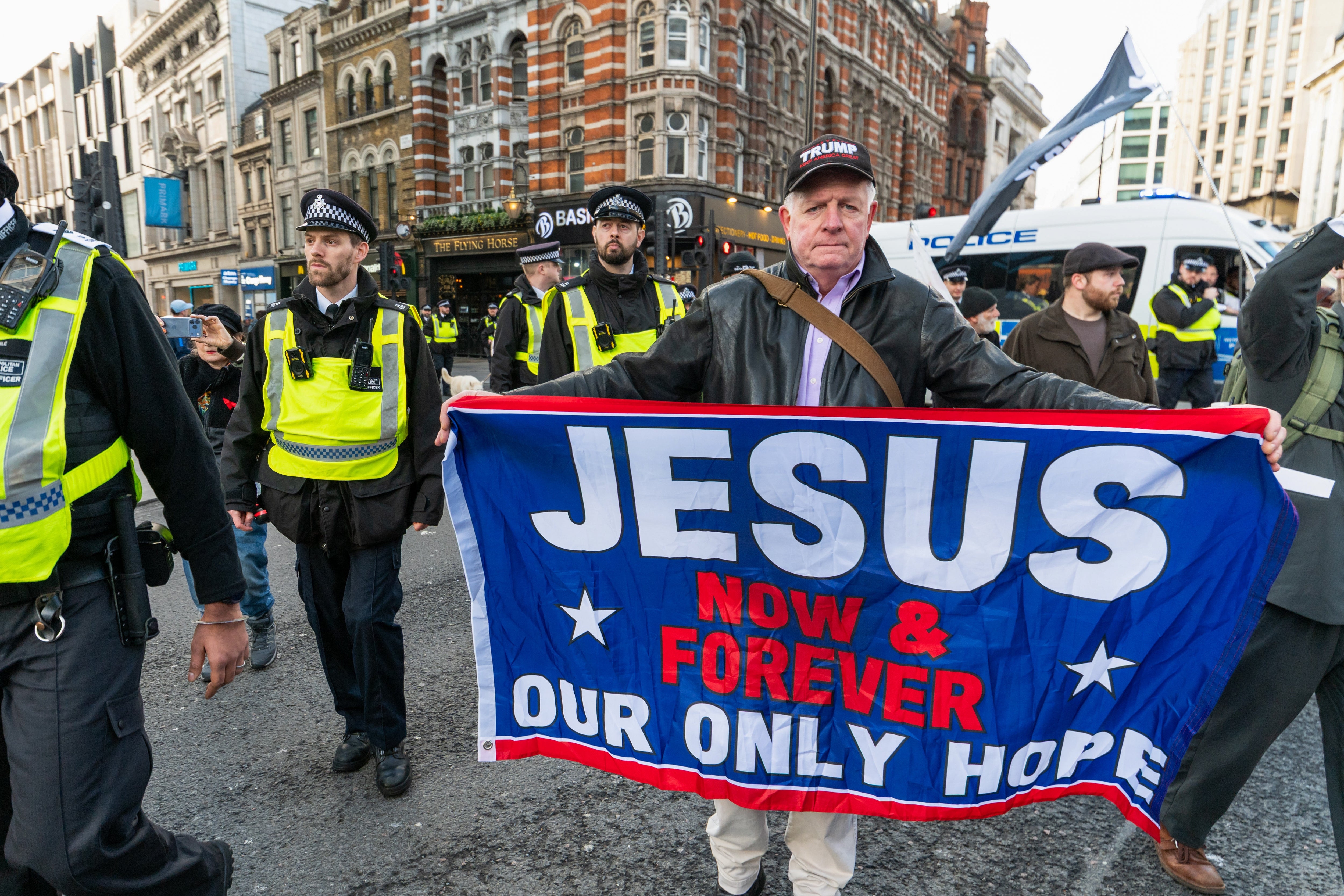 A protester holds a motion   speechmaking  "Jesus Now &amp; Forever Our Only Hope" astatine  a thoroughfare  demonstration, surrounded by constabulary  officers