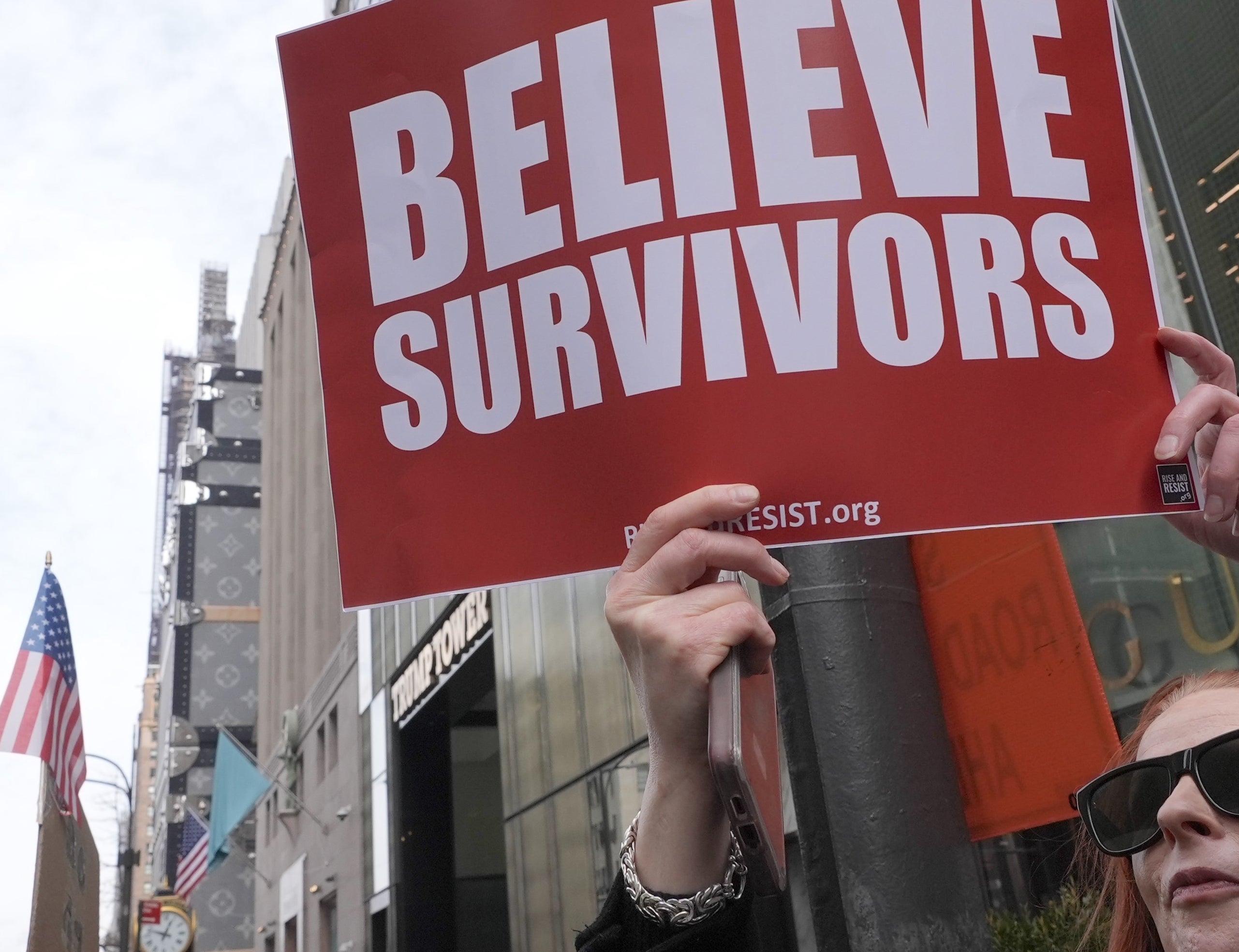 Person holding a motion   speechmaking  "Believe Survivors" during a thoroughfare  protest. Other participants and buildings are disposable   successful  the background