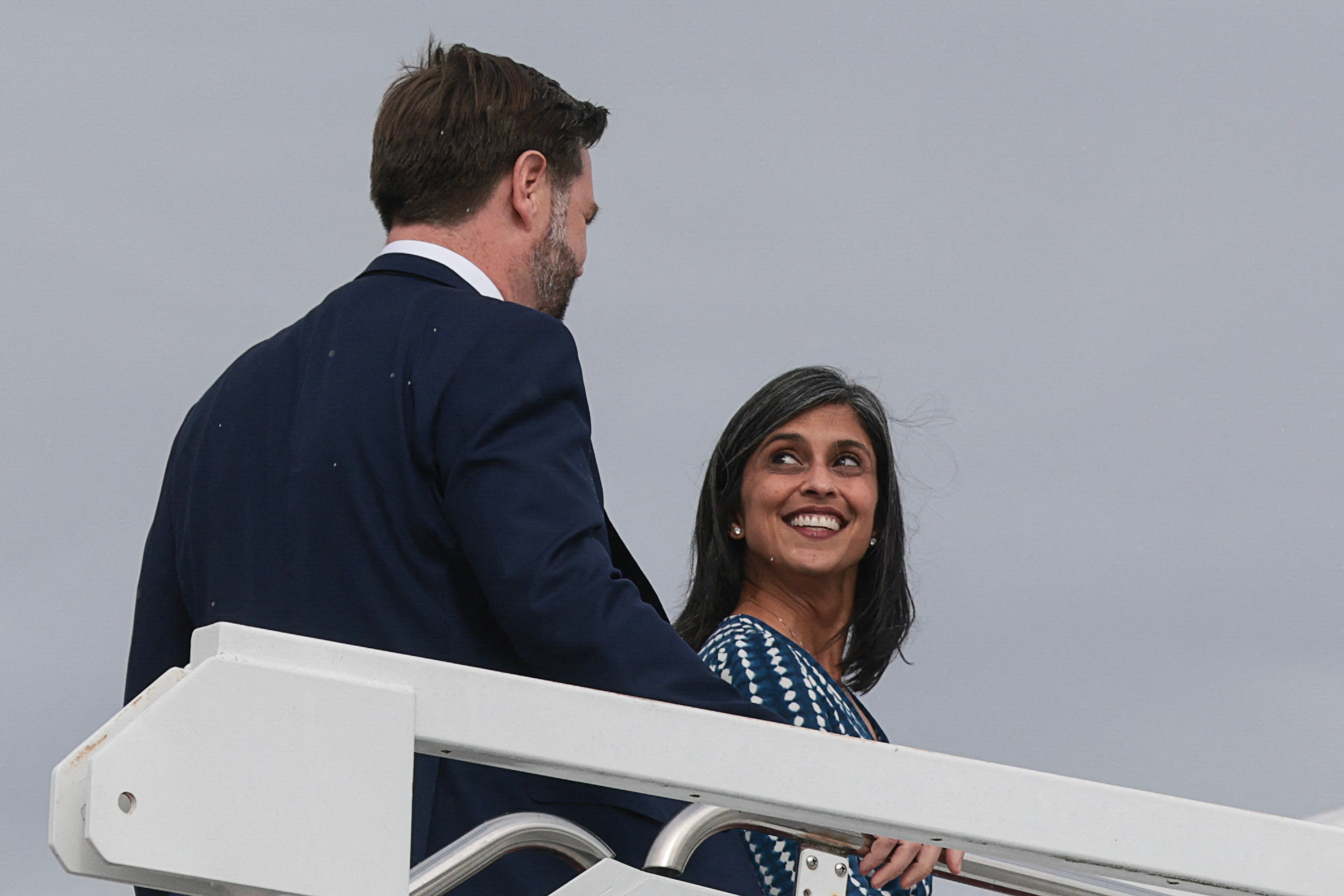 Two radical   smiling astatine  each   different   portion    walking up   airplane stairs