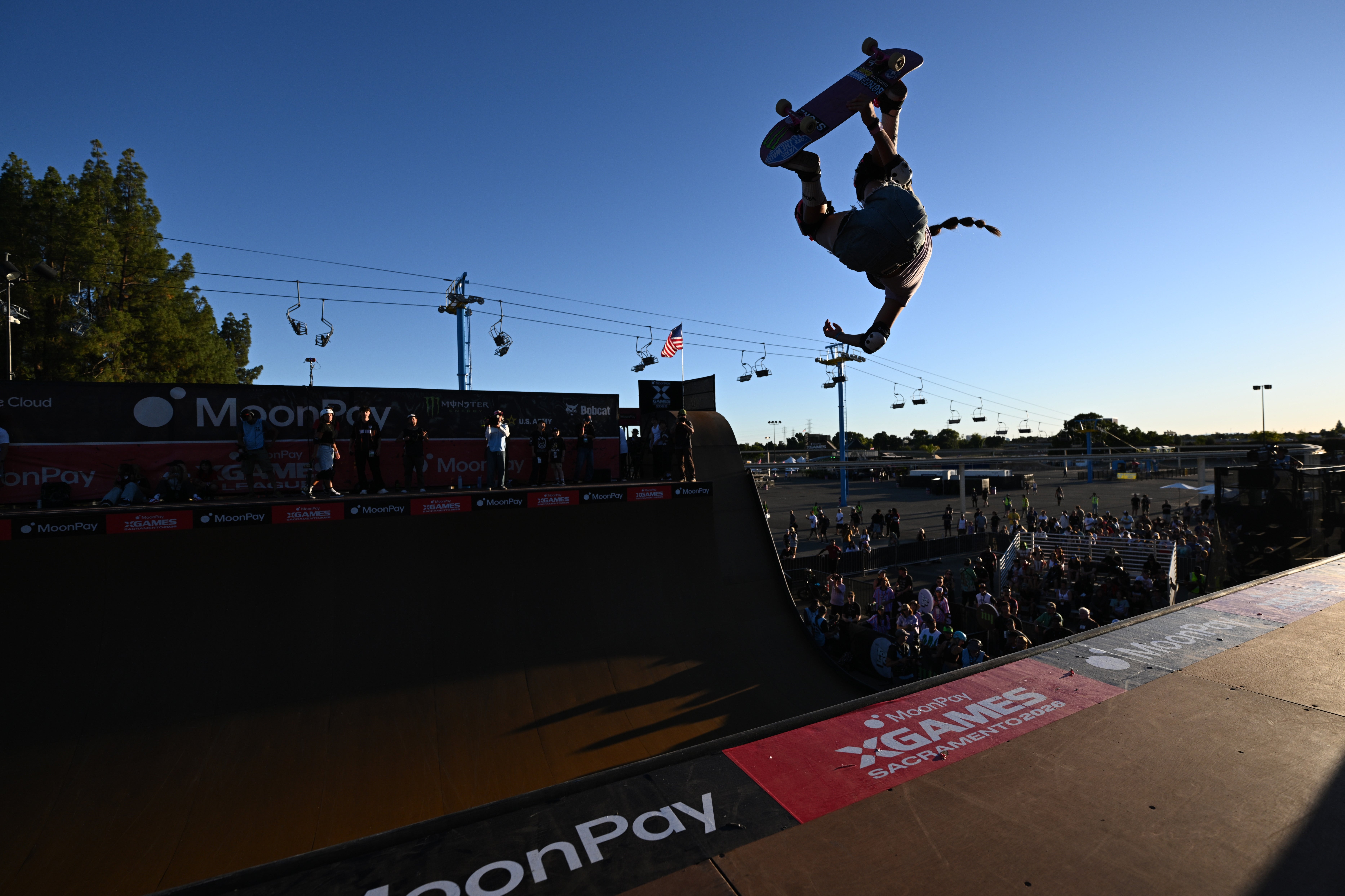 A skateboarder performs an aerial instrumentality   connected  a ramp astatine  an outdoor event, with an assemblage  watching below