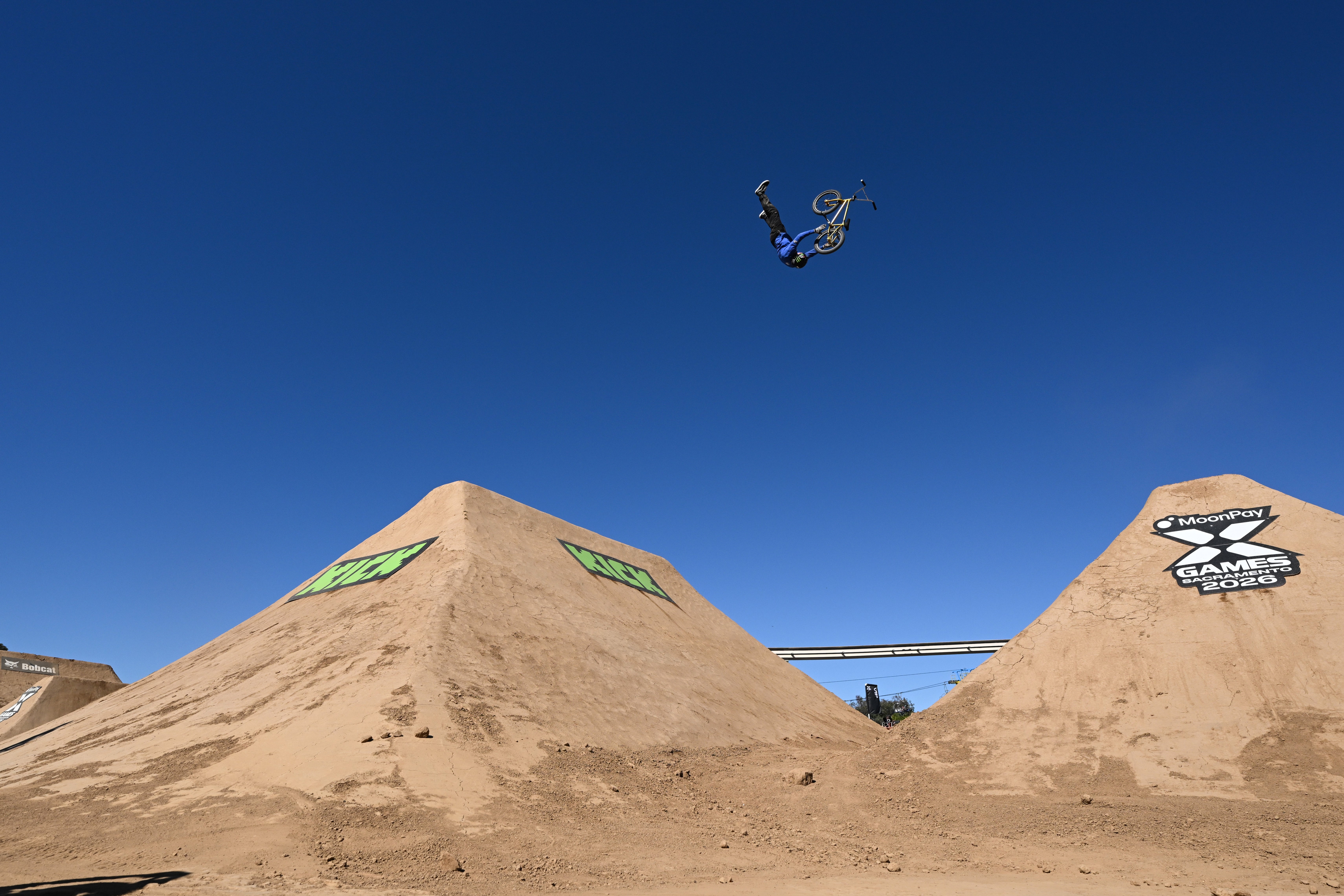 A BMX biker performs a mid-air flip supra  2  ample  ungraded  ramps astatine  an utmost  sports event