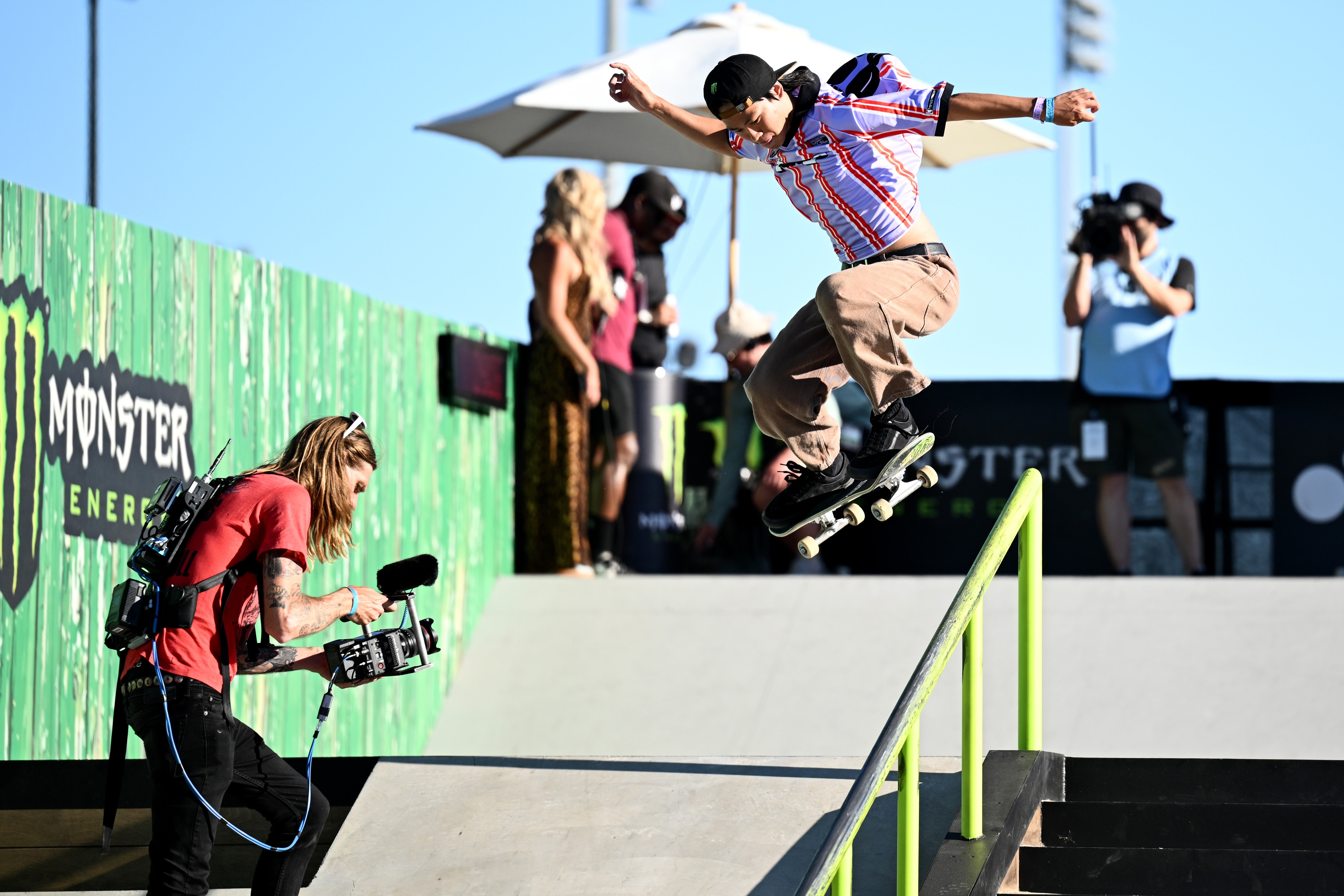 A skateboarder performs a instrumentality   down   a obstruction   portion    a cameraman captures the infinitesimal   astatine  an outdoor event