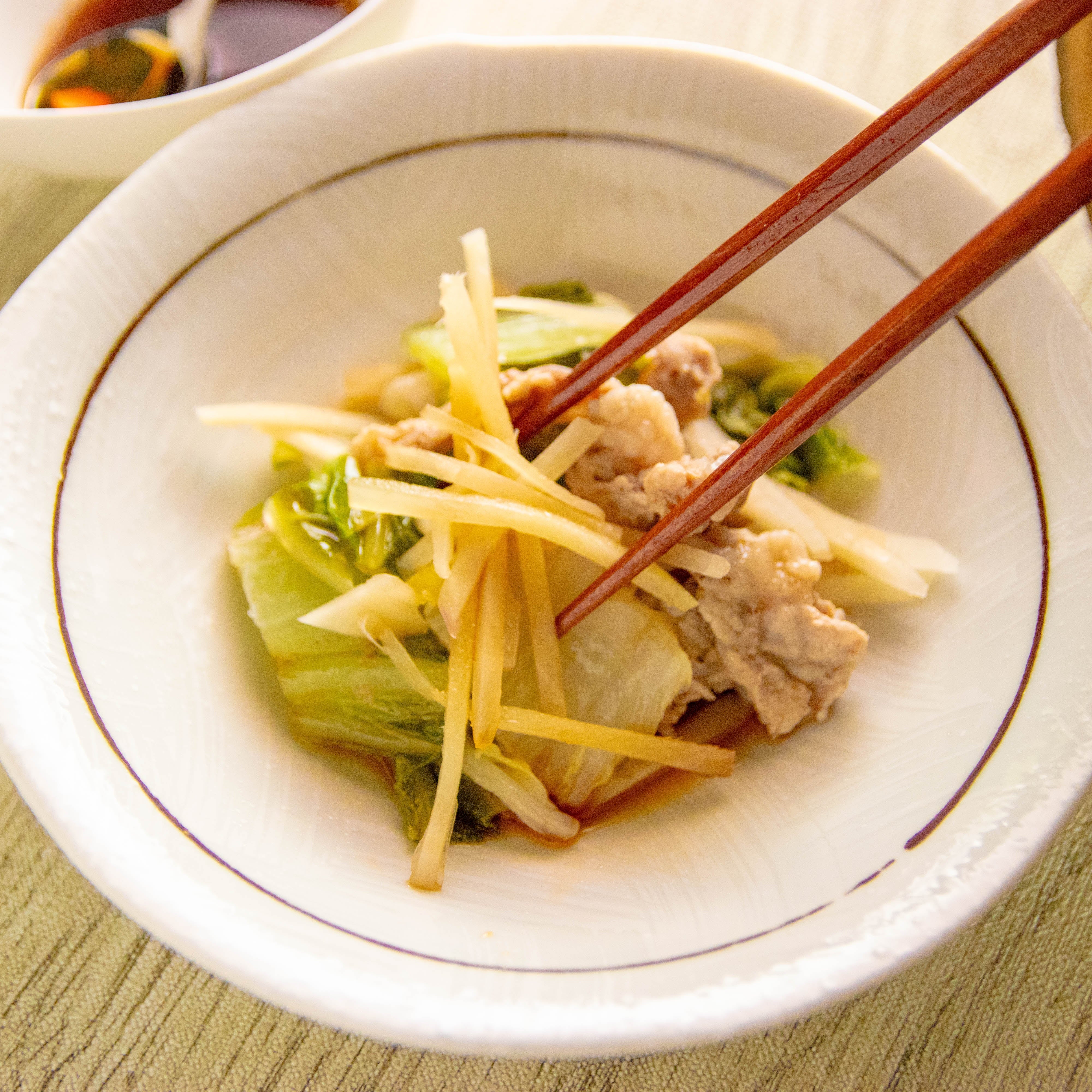 箸でひと口分を持ち上げられた、新しょうがの千切りがたっぷりと乗った柔らかな豚肉と白菜。