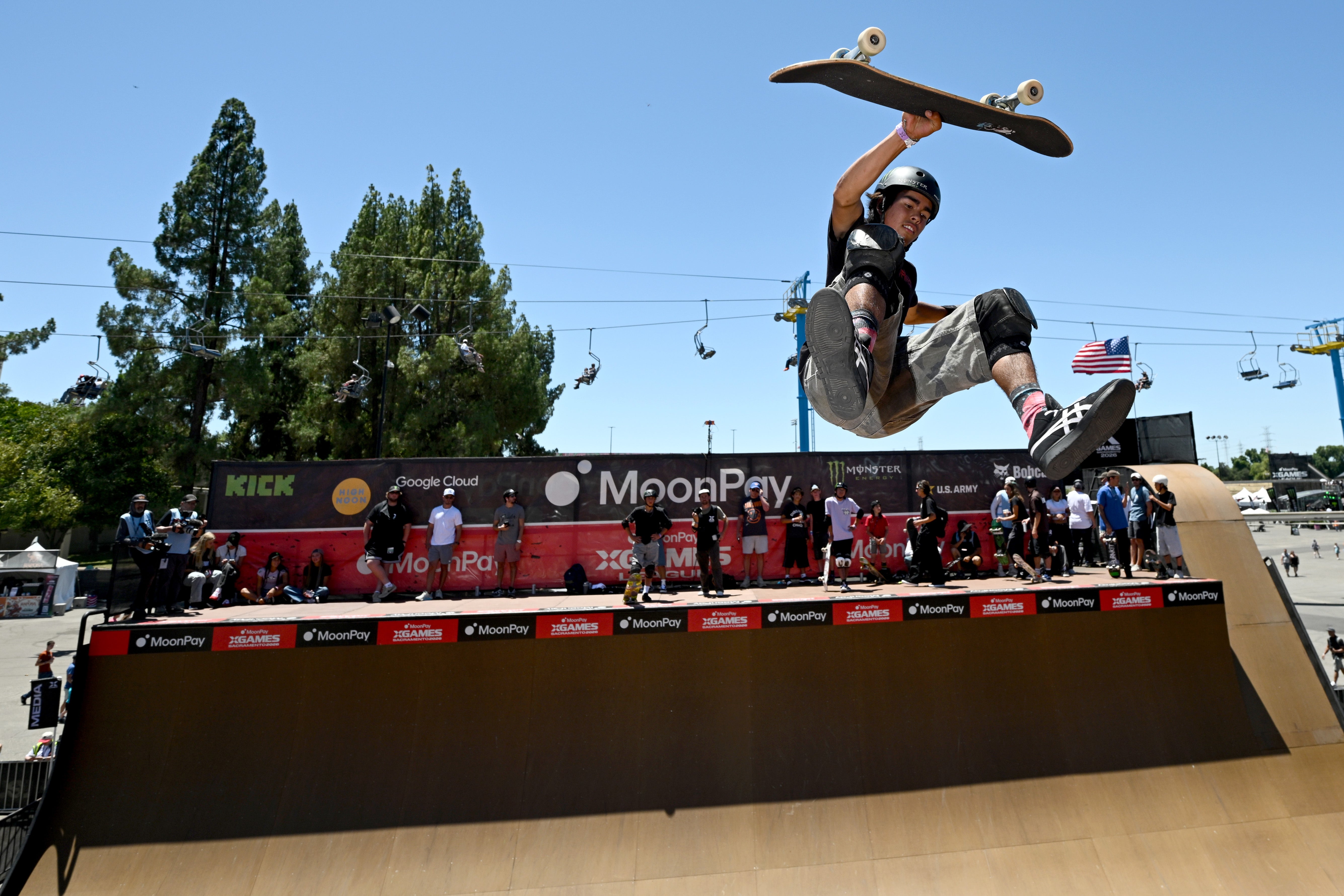 A skateboarder performs a high-flying instrumentality   supra  a ample  half-pipe during a competitory  event, with spectators watching below