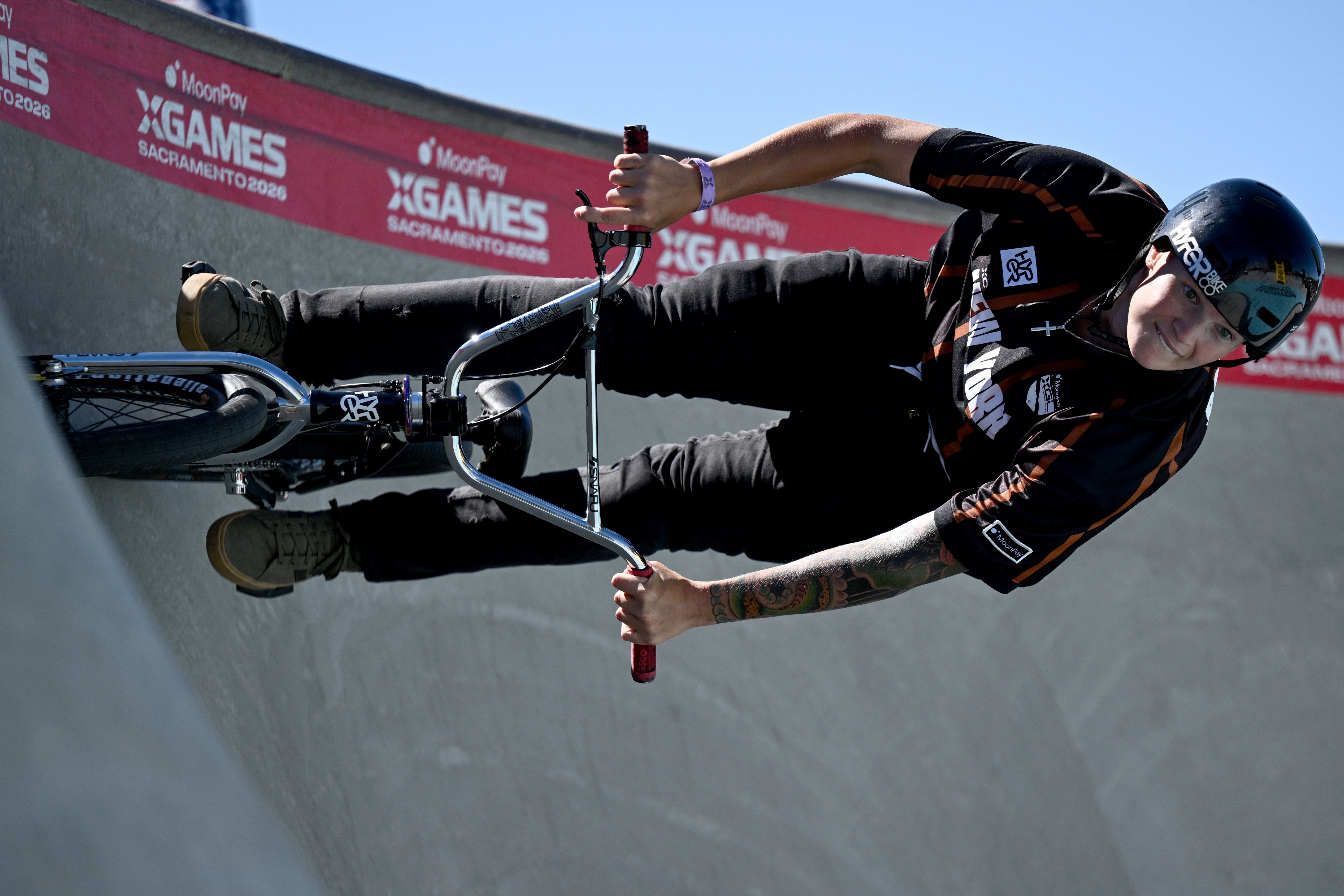 Person performing a BMX instrumentality   connected  a ramp astatine  X Games event, wearing a helmet and sports gear
