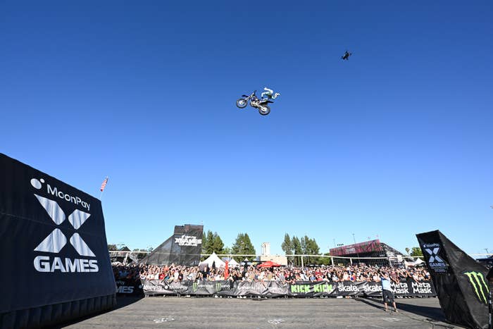Motorcyclist performs a precocious   leap  stunt astatine  X Games event, with a ample  assemblage  watching from below