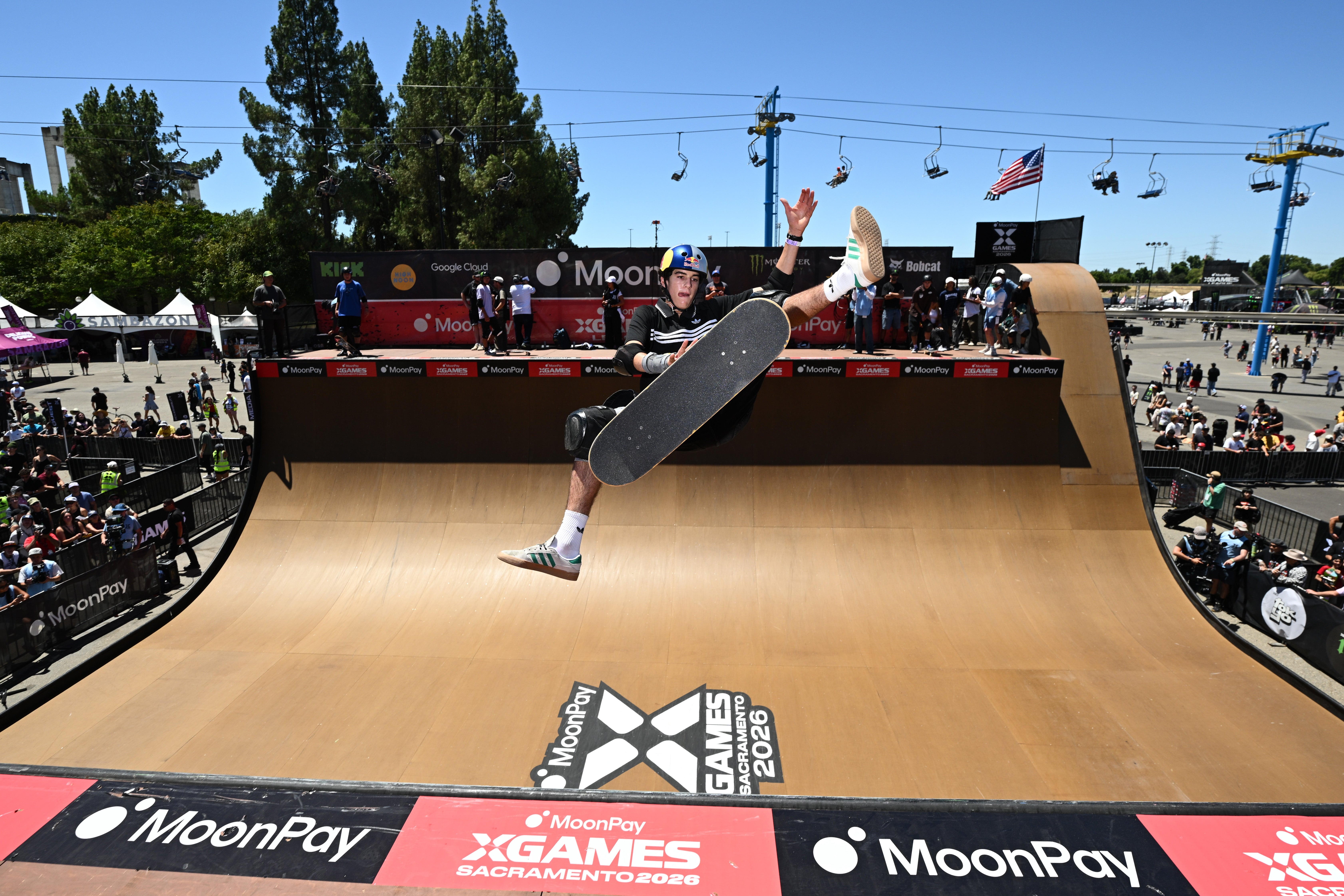A skateboarder performs a instrumentality   mid-air astatine  an X Games event, surrounded by spectators and lawsuit   signage