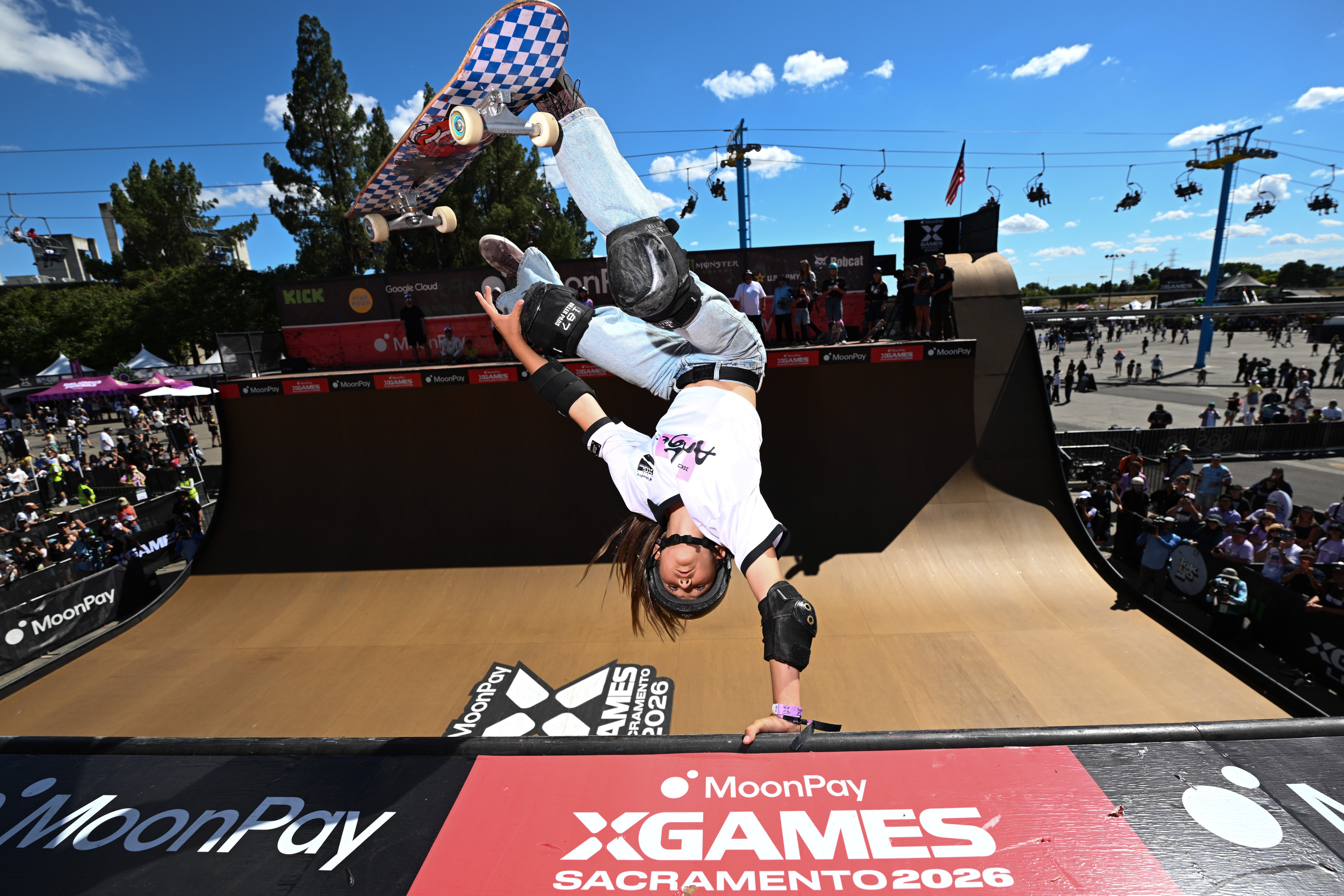 Skateboarder performs a handstand instrumentality   connected  a ramp astatine  the X Games event, wearing protective cogwheel  and casual sports attire