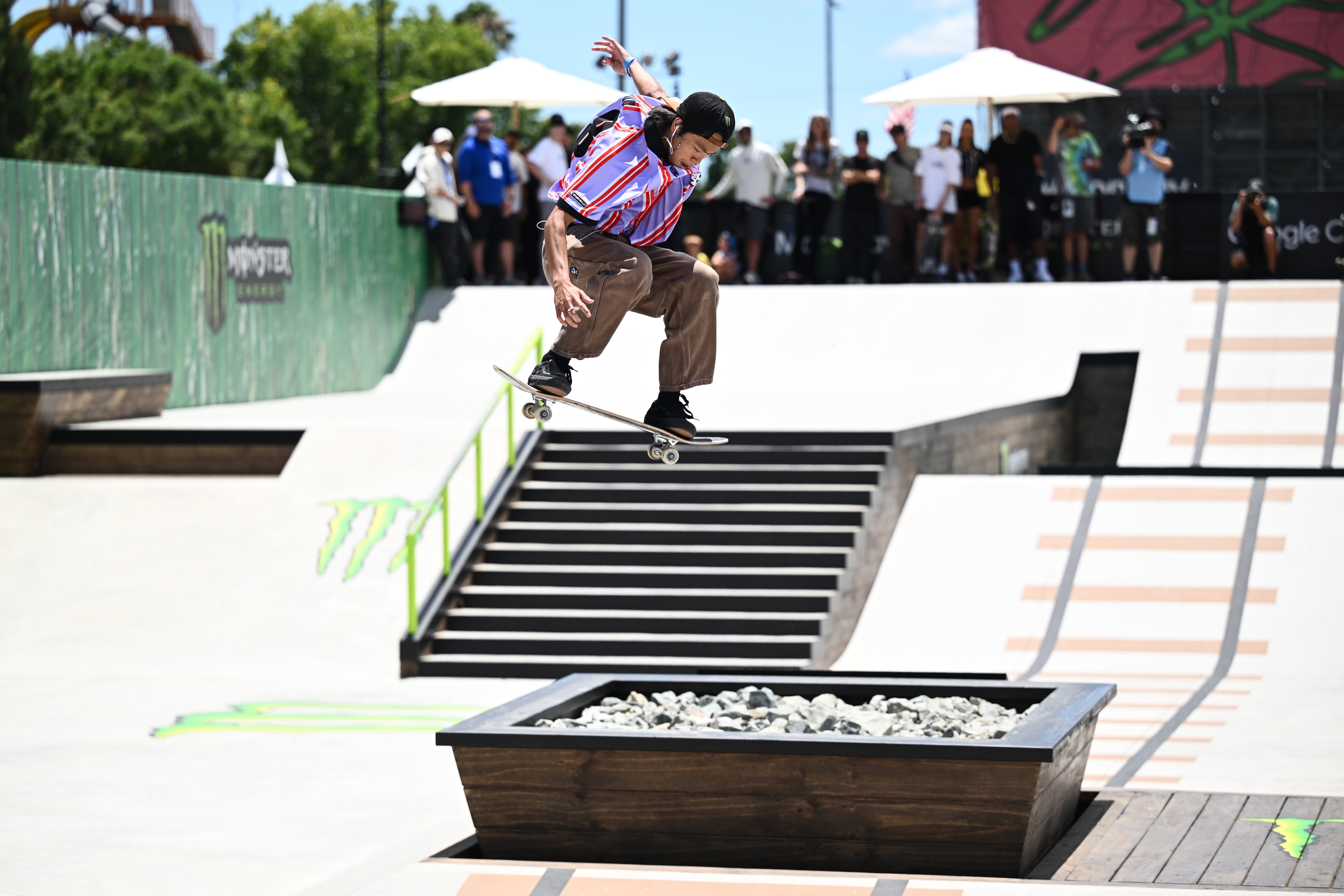 A skateboarder performs a instrumentality   implicit    a ledge astatine  a skateboarding event, with spectators successful  the background