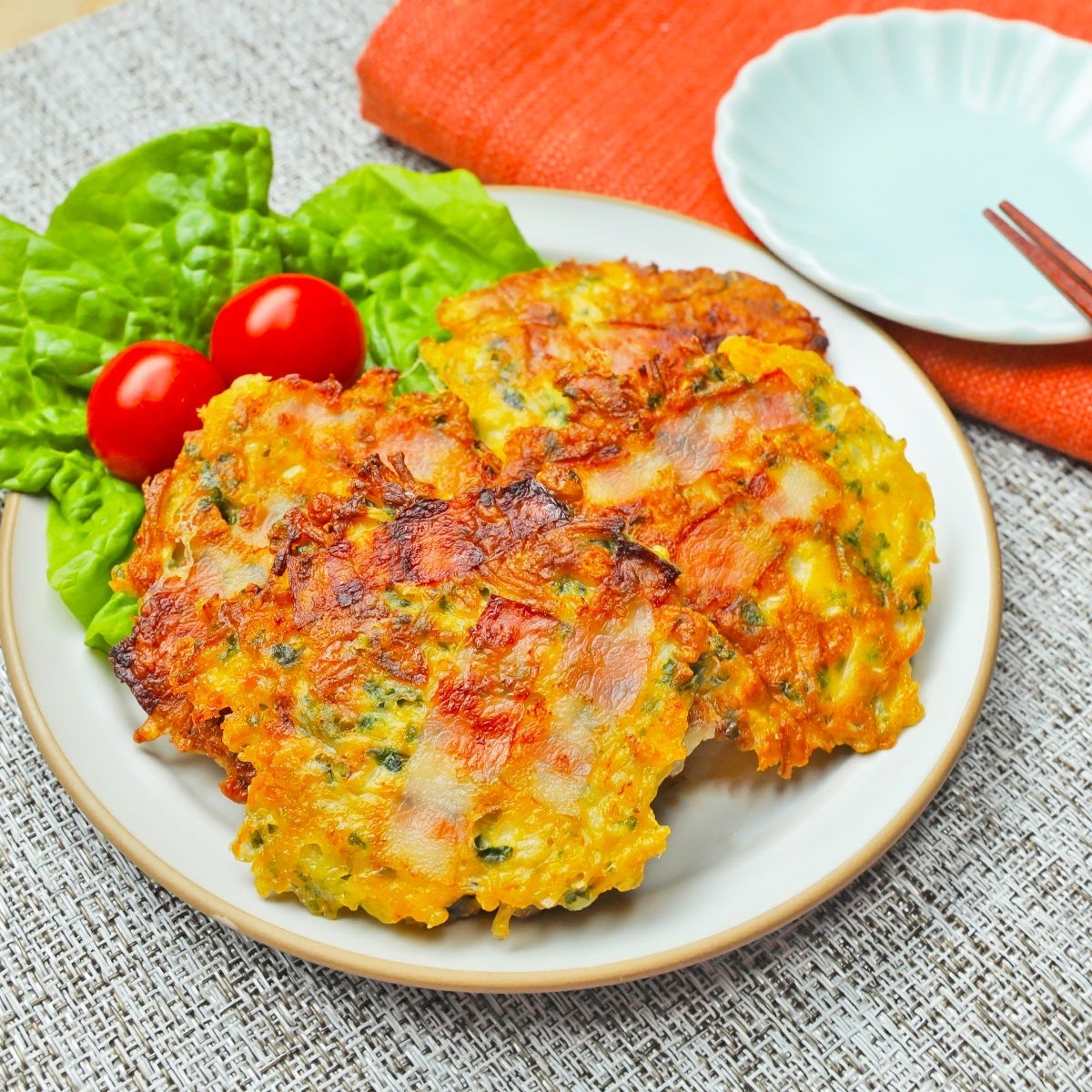 皿に盛られたえのきとベーコンの青のりチーズ焼き。付け合わせにレタスとプチトマト。
