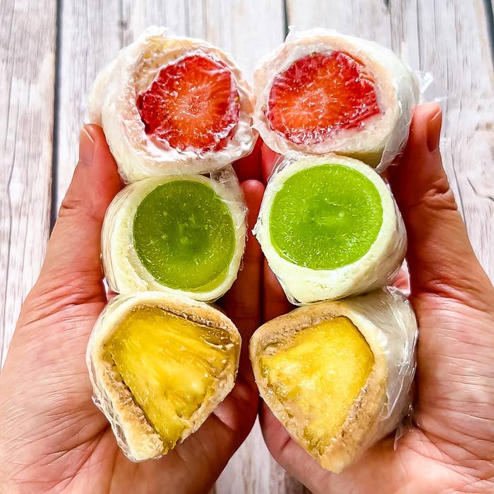 手にのせたフルーツサンドイッチ。上からいちご、マスカット、パイナップルが見える。