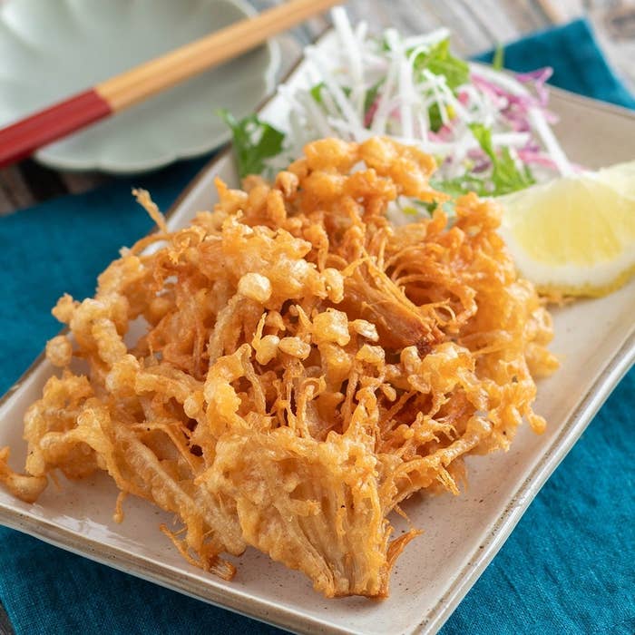 お皿に盛られたカリッと揚げたえのきの唐揚げ。レモンのくさ切りとサラダが添えられている。