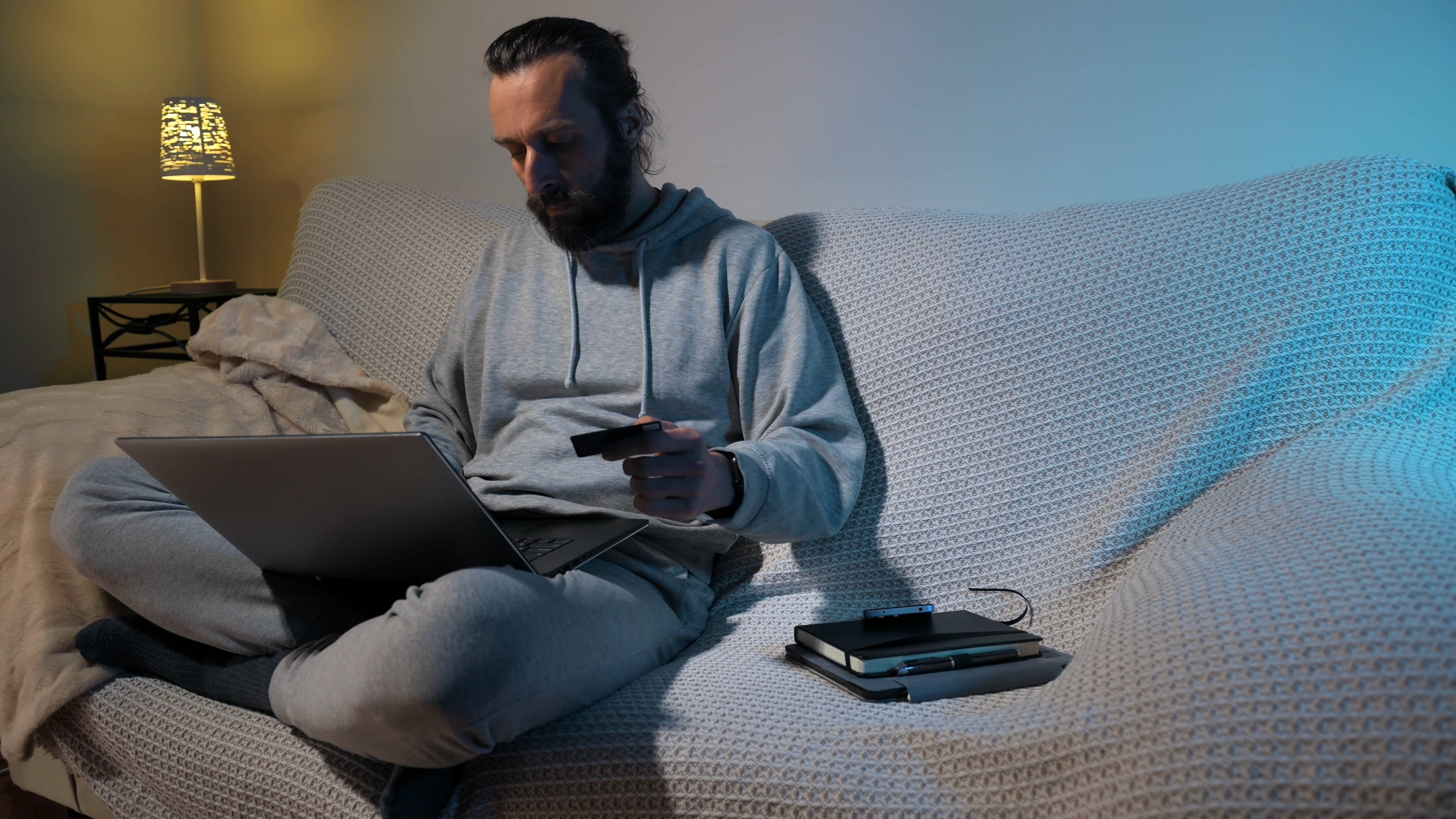 A idiosyncratic successful casual location attire sitting connected a couch, holding a recognition paper portion utilizing a laptop, perchance buying oregon managing finances online