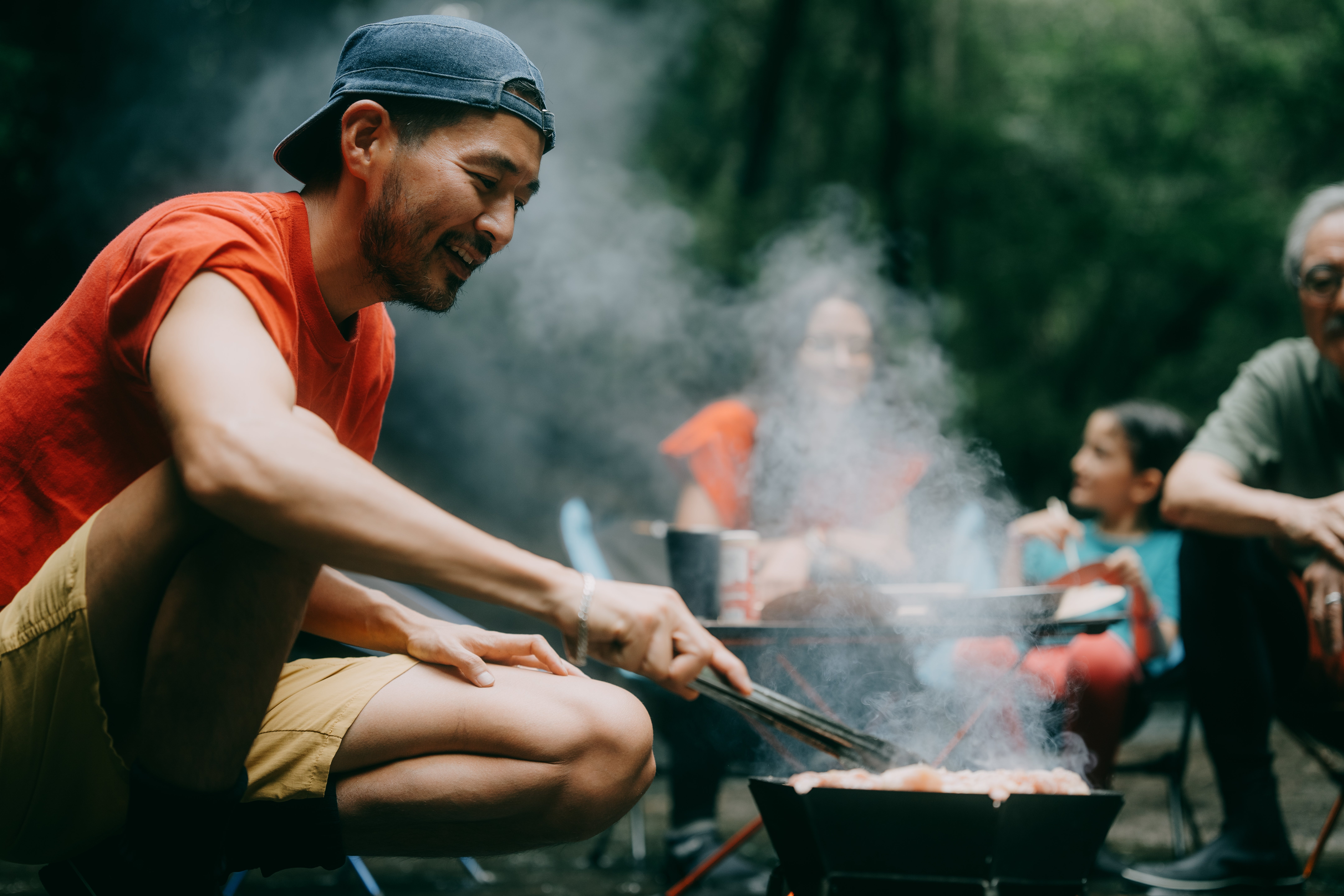 Man grilling outdoors with friends oregon household seated nearby, enjoying a relaxed, steadfast outdoor gathering
