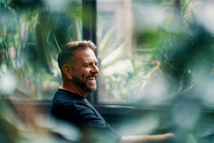 Smiling antheral   sitting amidst lush indoor plants, appearing relaxed and content, perchance  highlighting a wellness  oregon  wellness topic